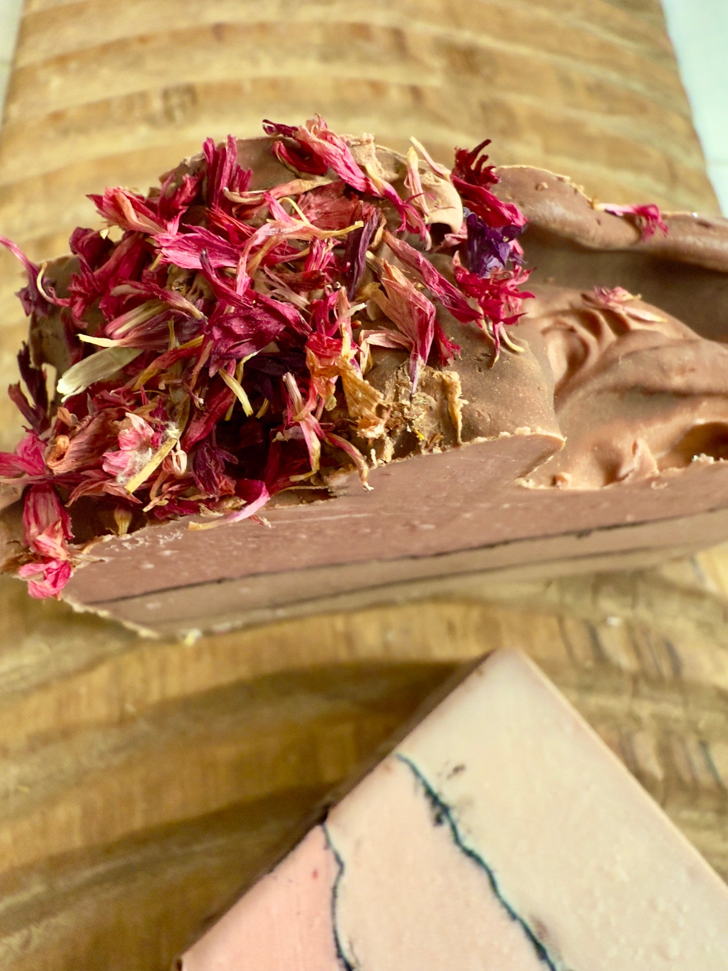 Layered rose and cream soap bar with charcoal line and pink cornflower topping