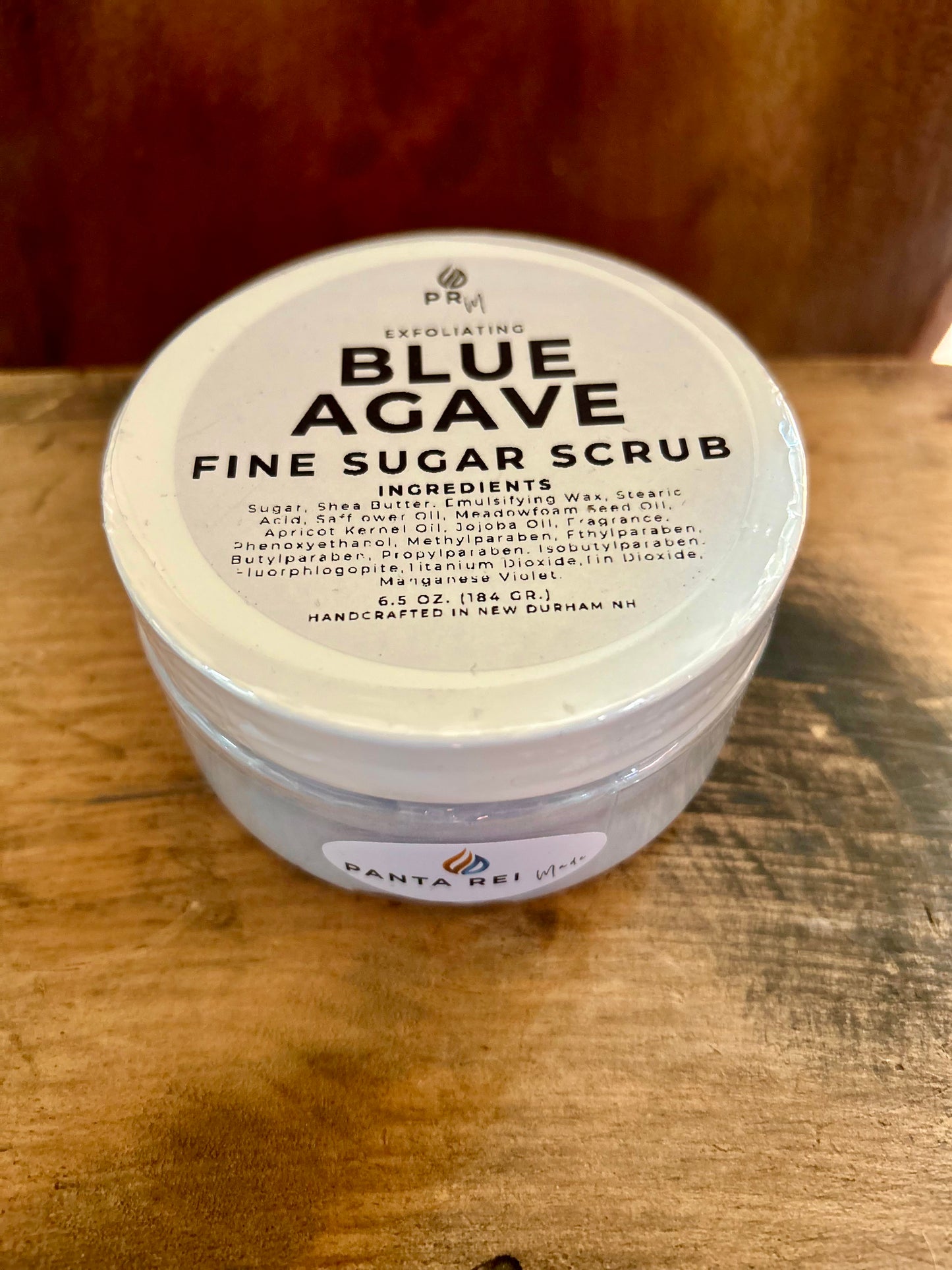 Container of Blue Agave Fine Sugar Scrub on a wooden surface