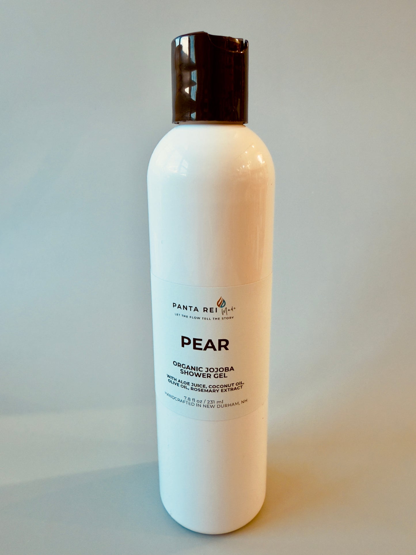 White bottle with black cap labeled Pear Organic Jojoba Shower Gel.