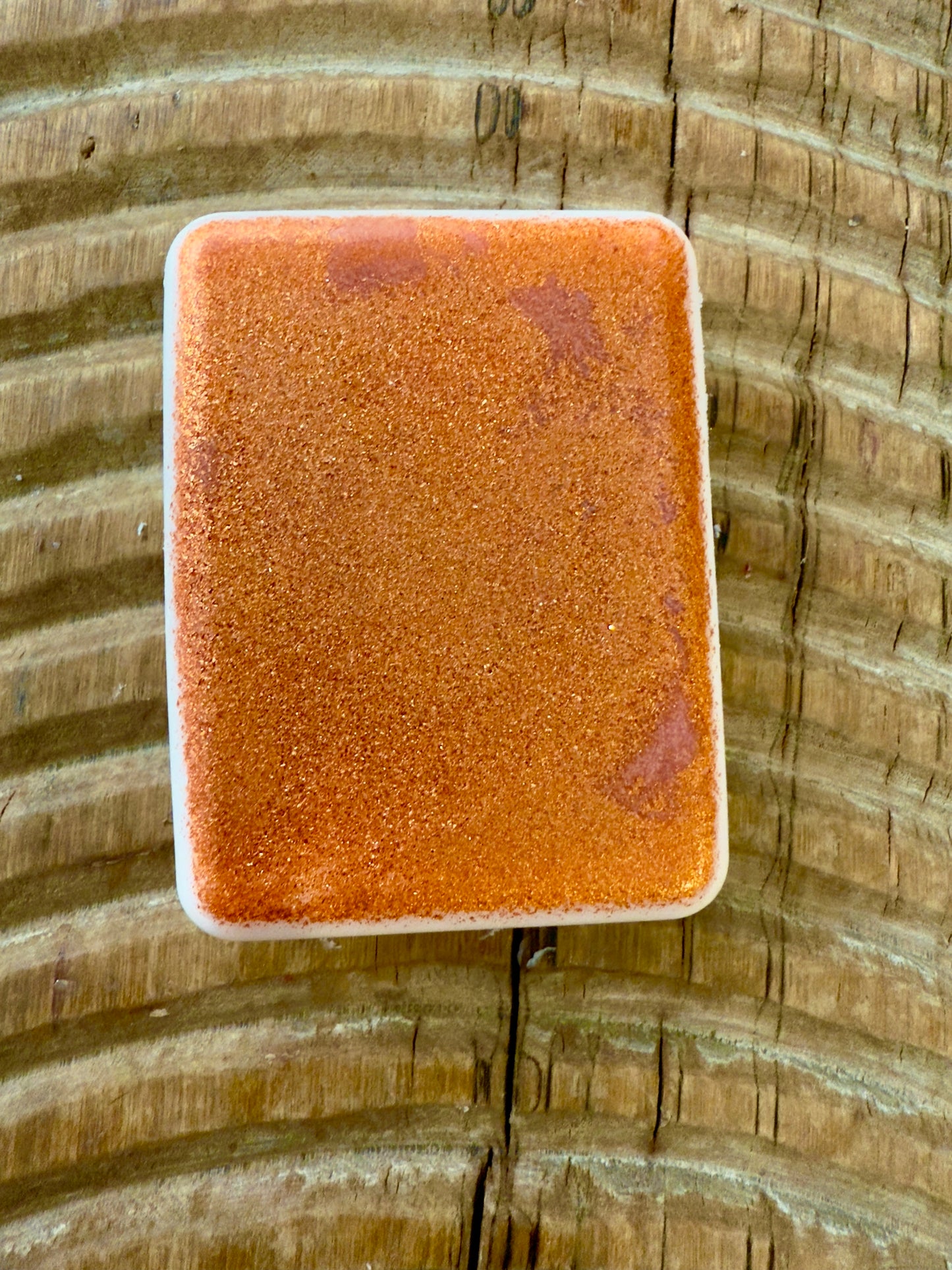 Rectangular copper-mica shampoo bar with a warm, metallic sheen on a wood surface.