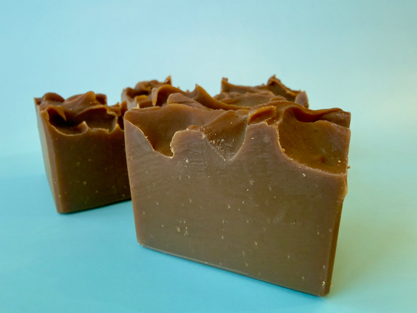 Hand-cut golden brown soap chunks with softly textured top on a light background