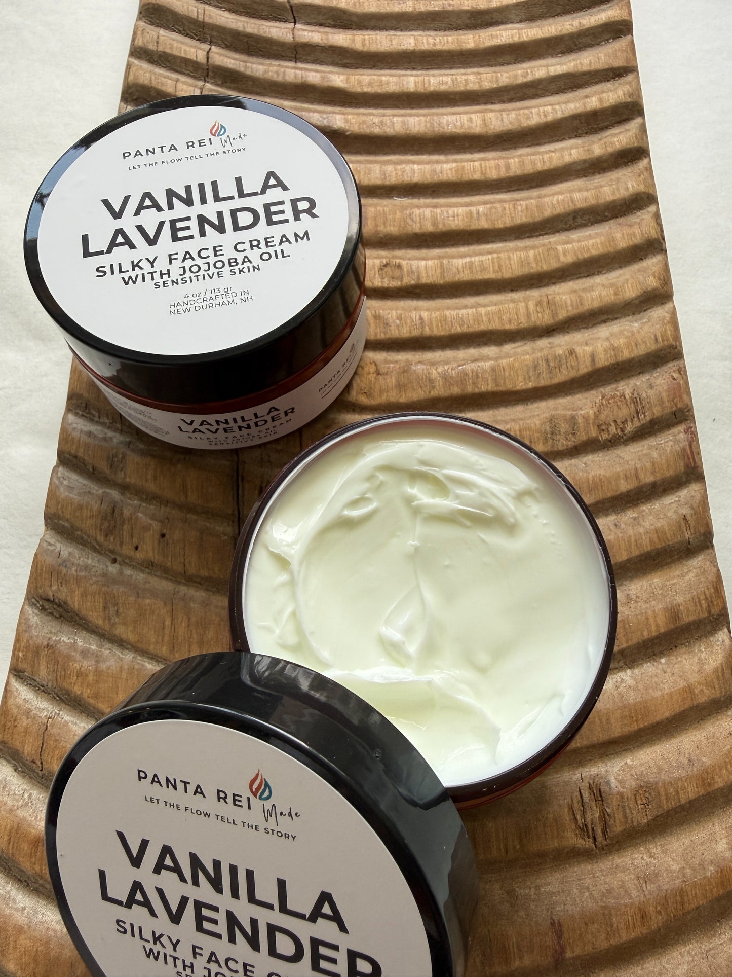 Vanilla lavender face cream jar with lid removed on a wooden board