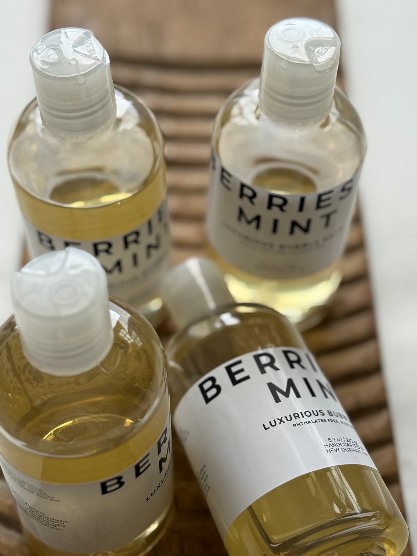 Berries + Mint luxurious bubble bath bottles on a carved wooden tray.