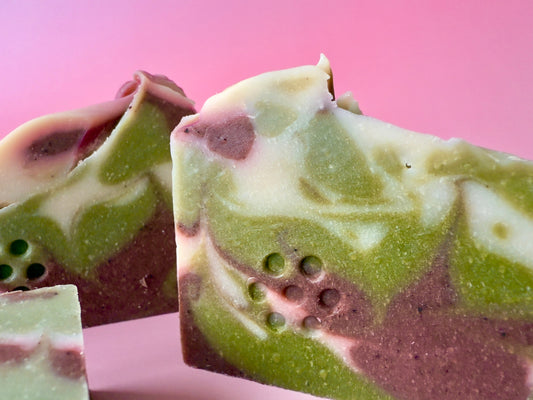 Handcrafted soap bars with soft green and cream natural tones, colored with plant-based ingredients.