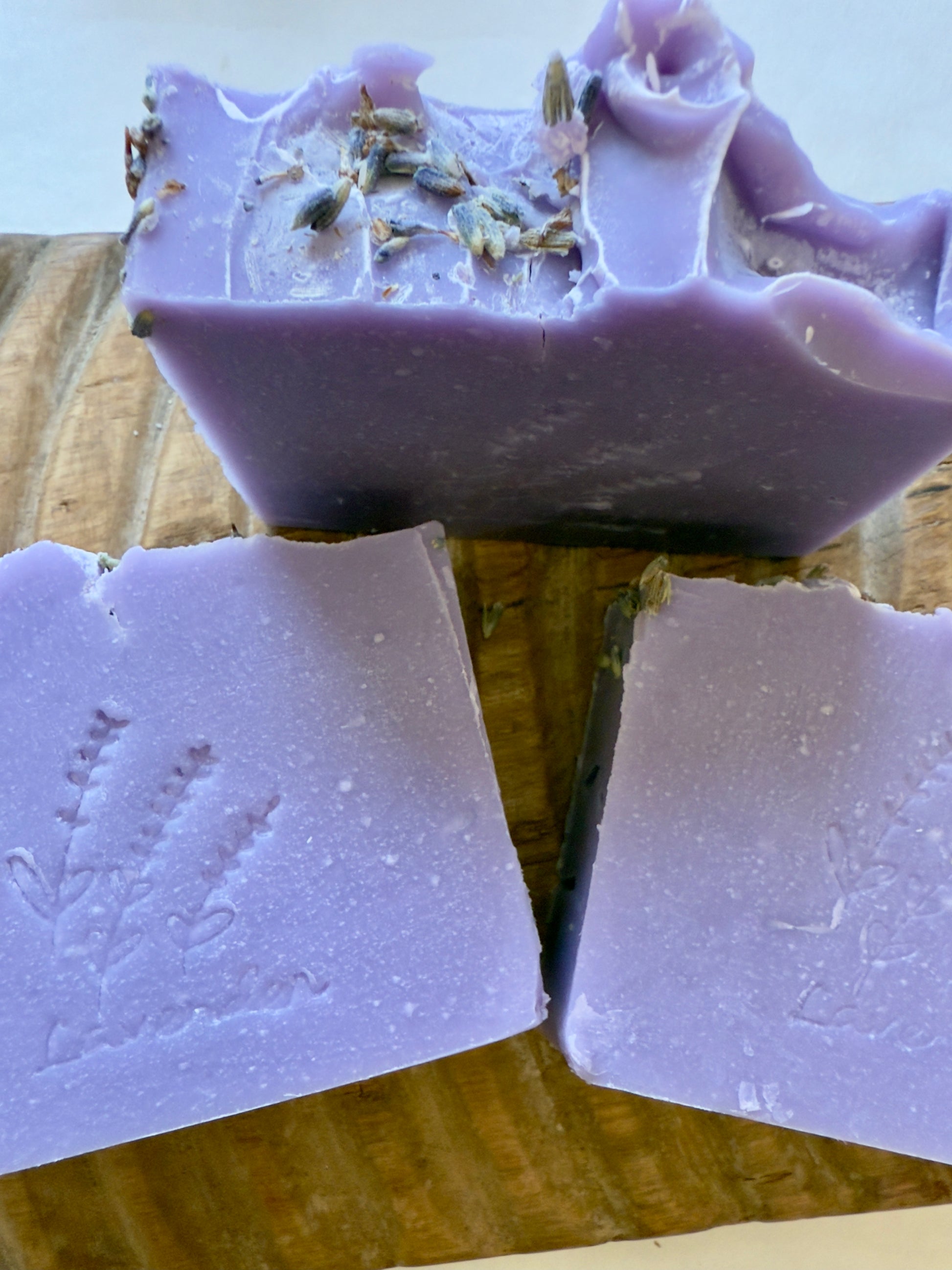Lavender CP soap bars with a stamped lavender sprig design on a wood board.