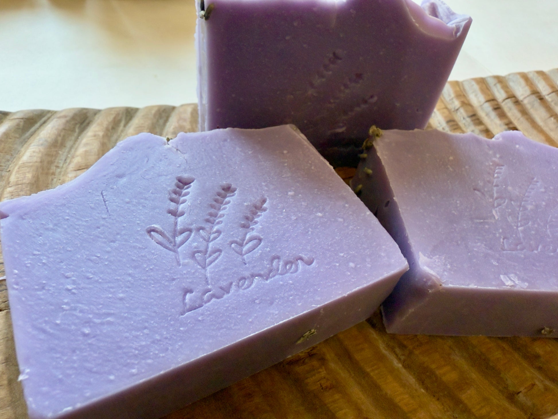 Lavender CP soap bars with a stamped lavender sprig design on a wood board.