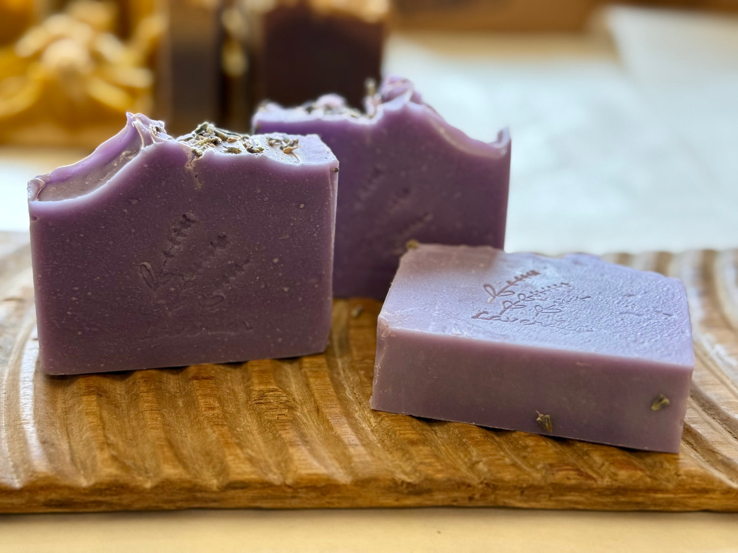 Lavender CP soap bars with a stamped lavender sprig design on a wood board.