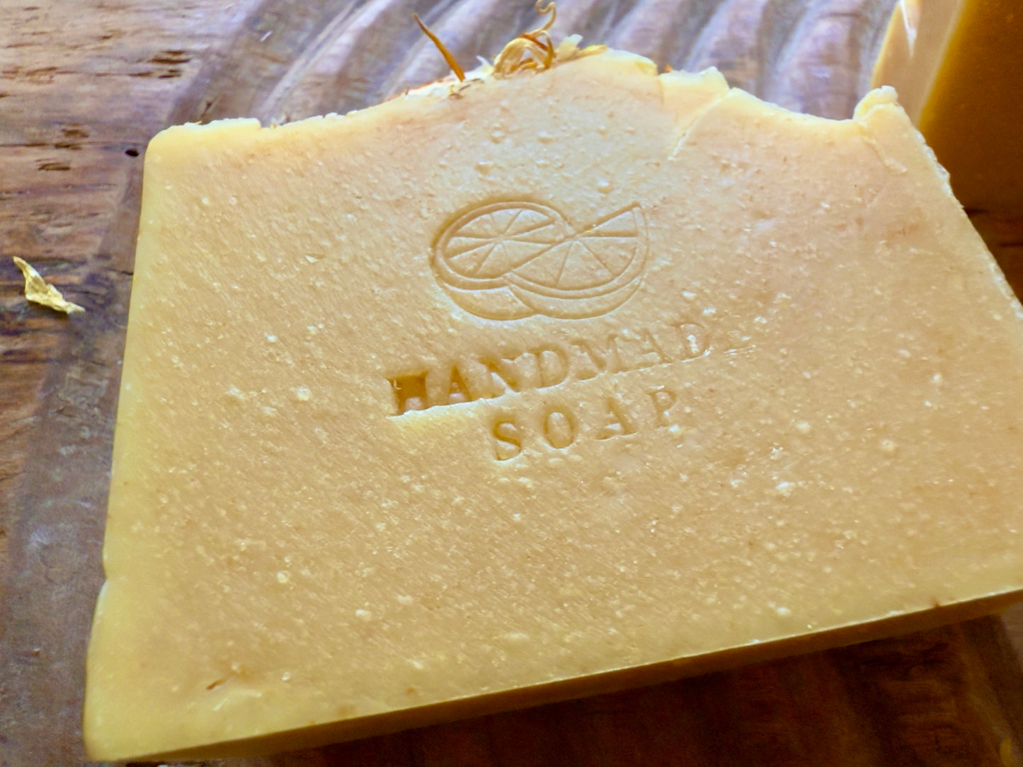 Handcrafted citrus soap with orange peel powder and calendula petals and dried orange slice on top