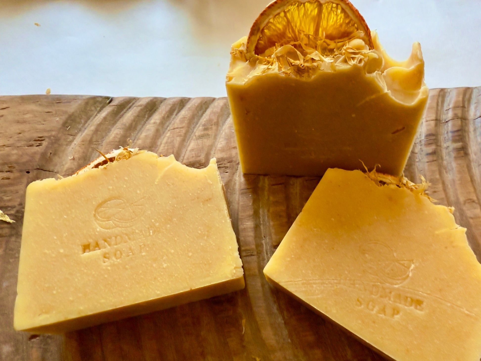 Handcrafted citrus soap with orange peel powder and calendula petals and dried orange slice on top