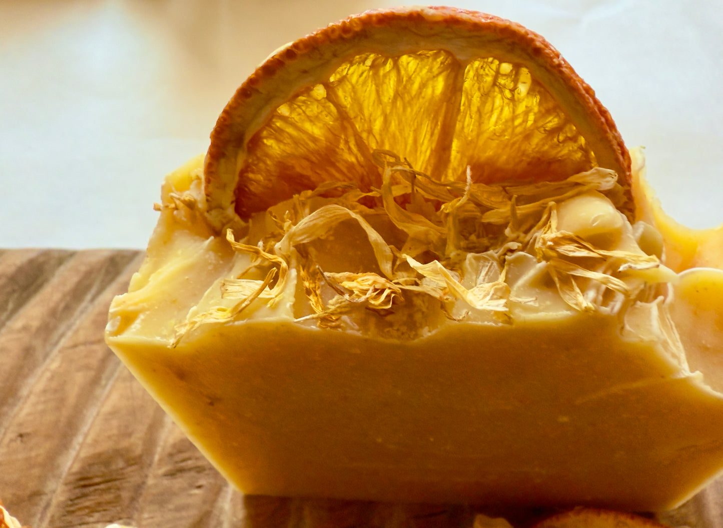 Handcrafted citrus soap with orange peel powder and calendula petals and dried orange slice on top