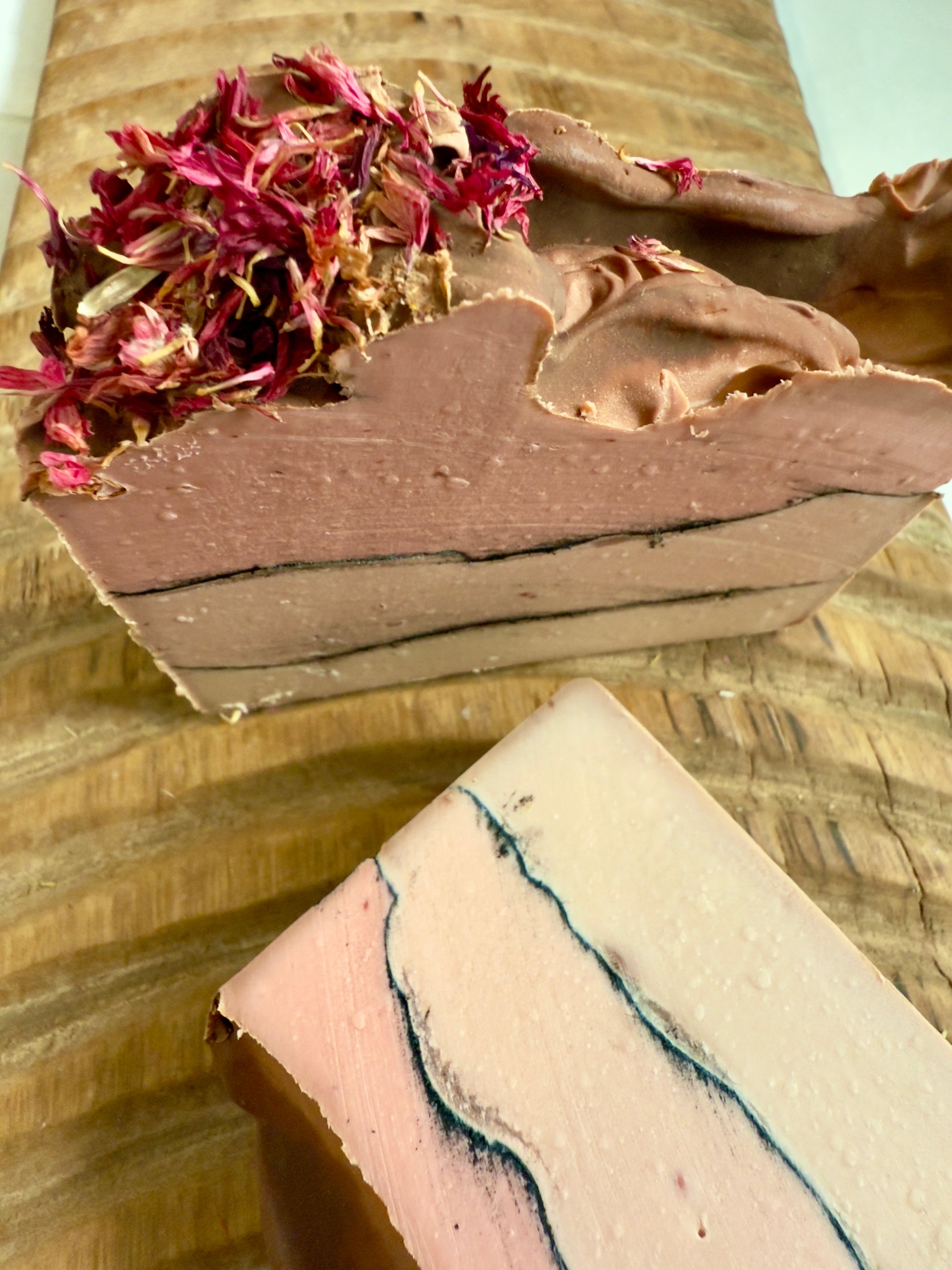 Layered rose and cream soap bar with charcoal line and pink cornflower topping