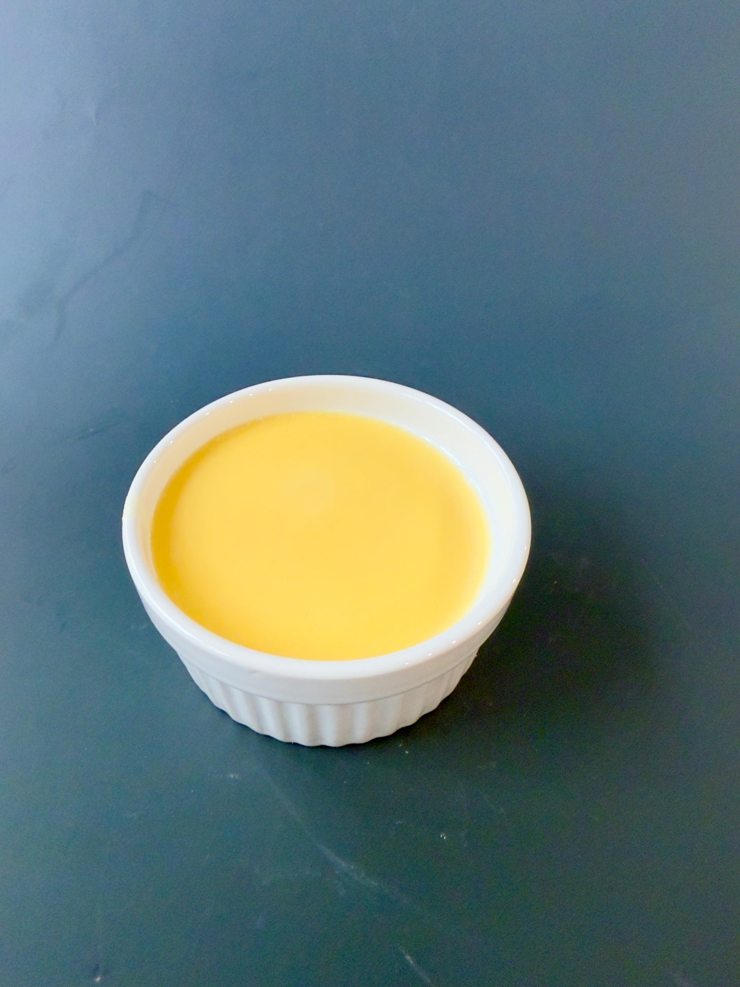 “Orange solid dish soap poured into white ceramic ramekin”