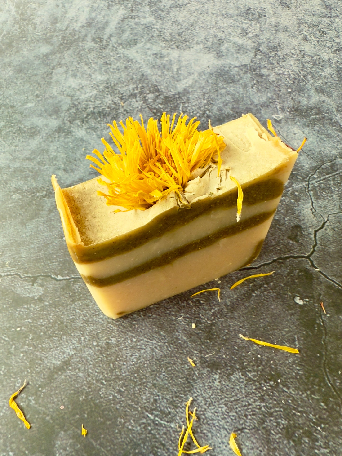 Bar of soap with yellow dried flowers on a gray surface