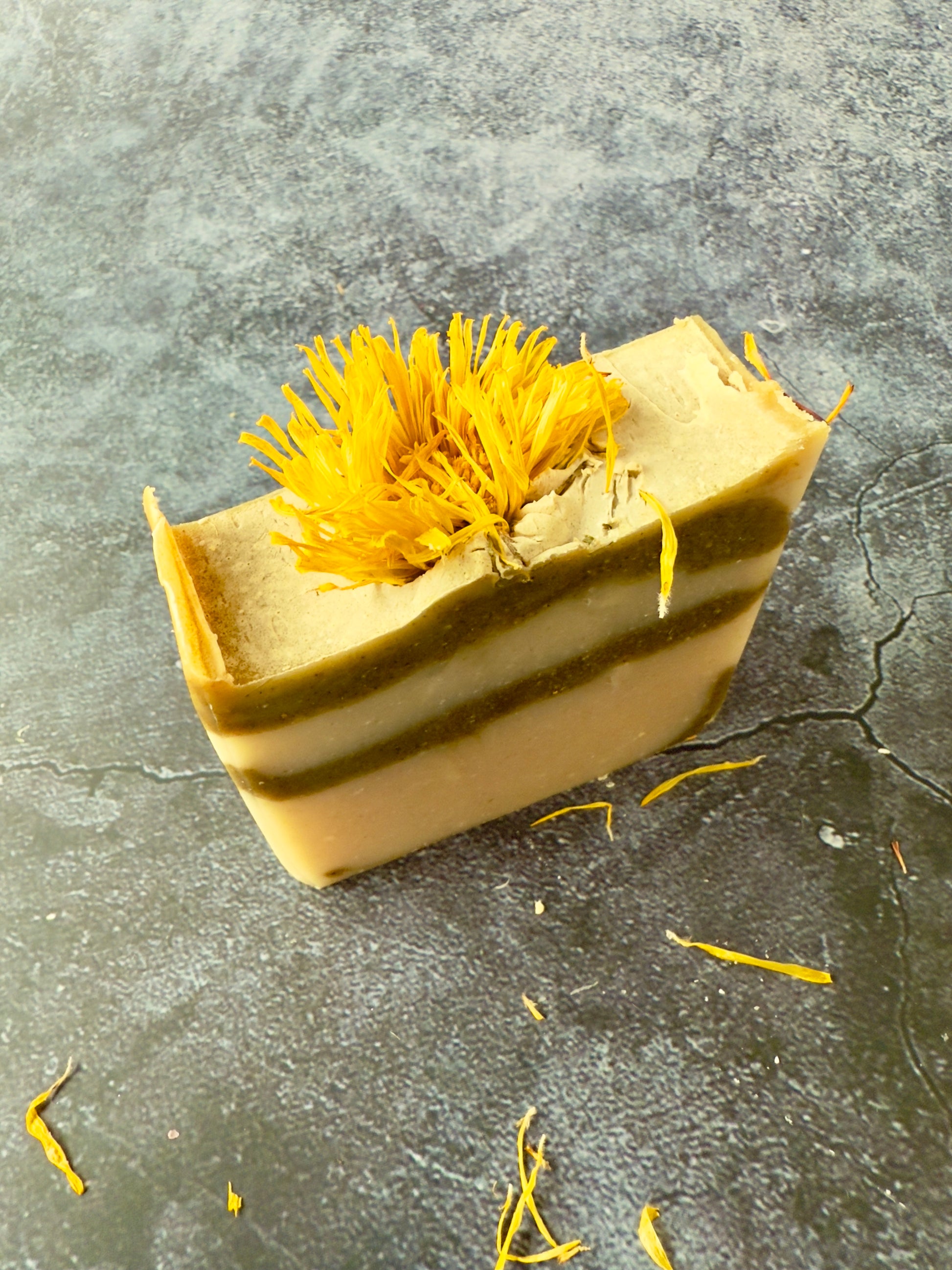 Bar of soap with yellow dried flowers on a gray surface