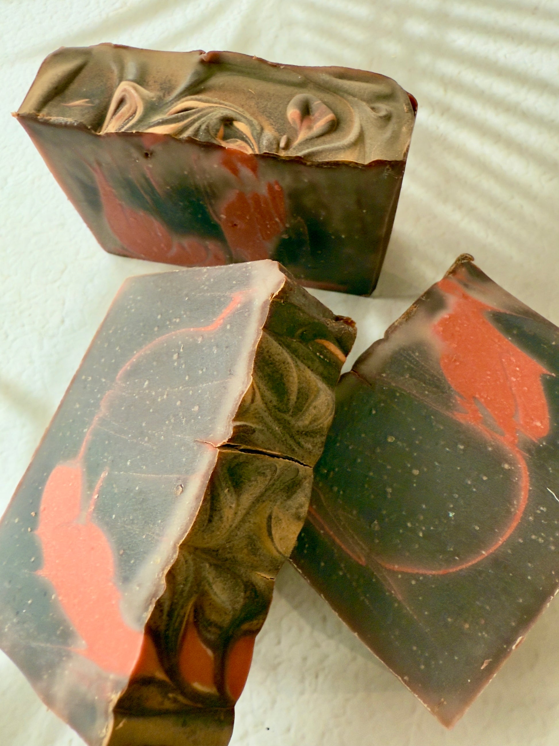 Brown and red swirled artisan soap with a creamy textured top and warm-toned marbled interior.