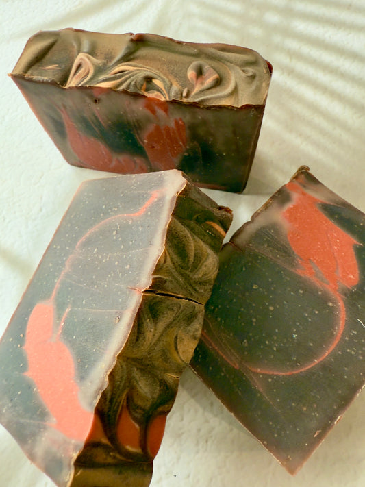 Brown and red swirled artisan soap with a creamy textured top and warm-toned marbled interior.