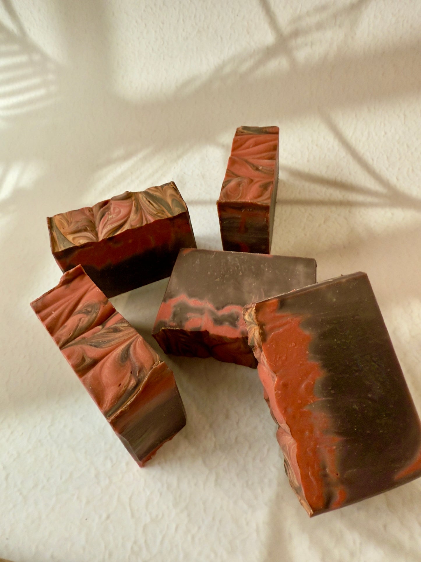 Brown and red swirled artisan soap with a creamy textured top and warm-toned marbled interior.