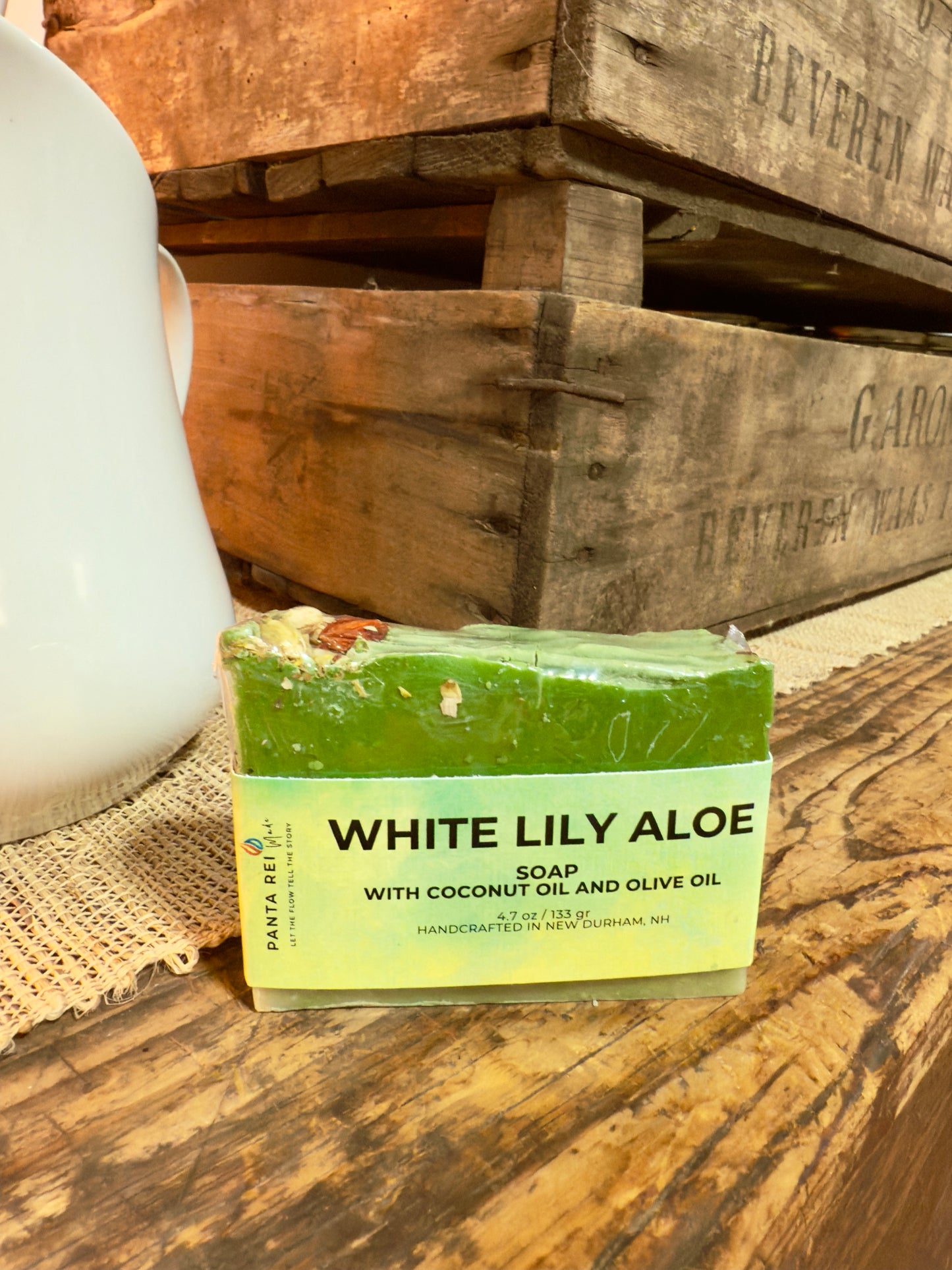 Green lily-and-aloe soap bar with a textured top and floral botanicals, wrapped in a White Lily Aloe label.