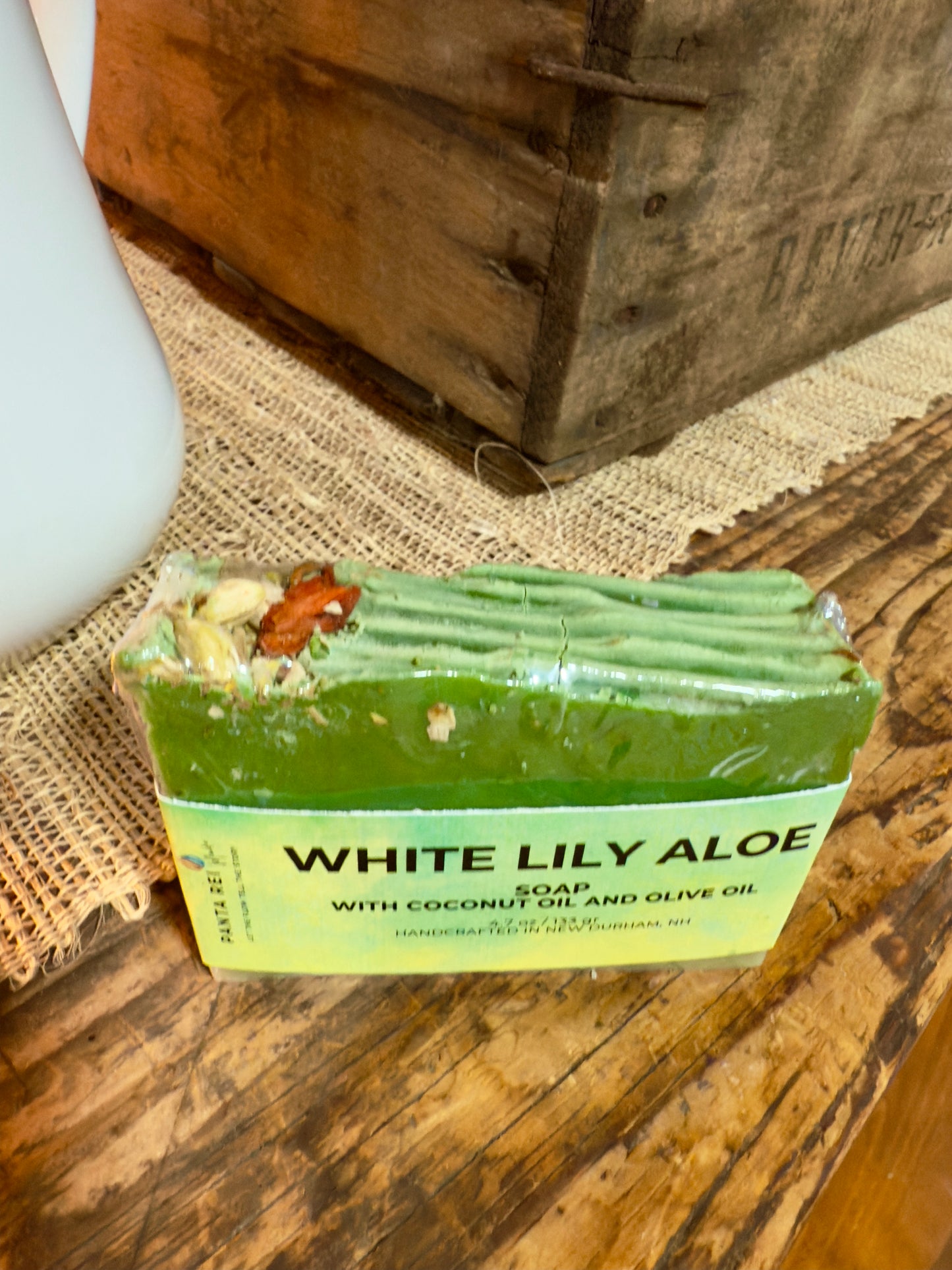Green lily-and-aloe soap bar with a textured top and floral botanicals, wrapped in a White Lily Aloe label.