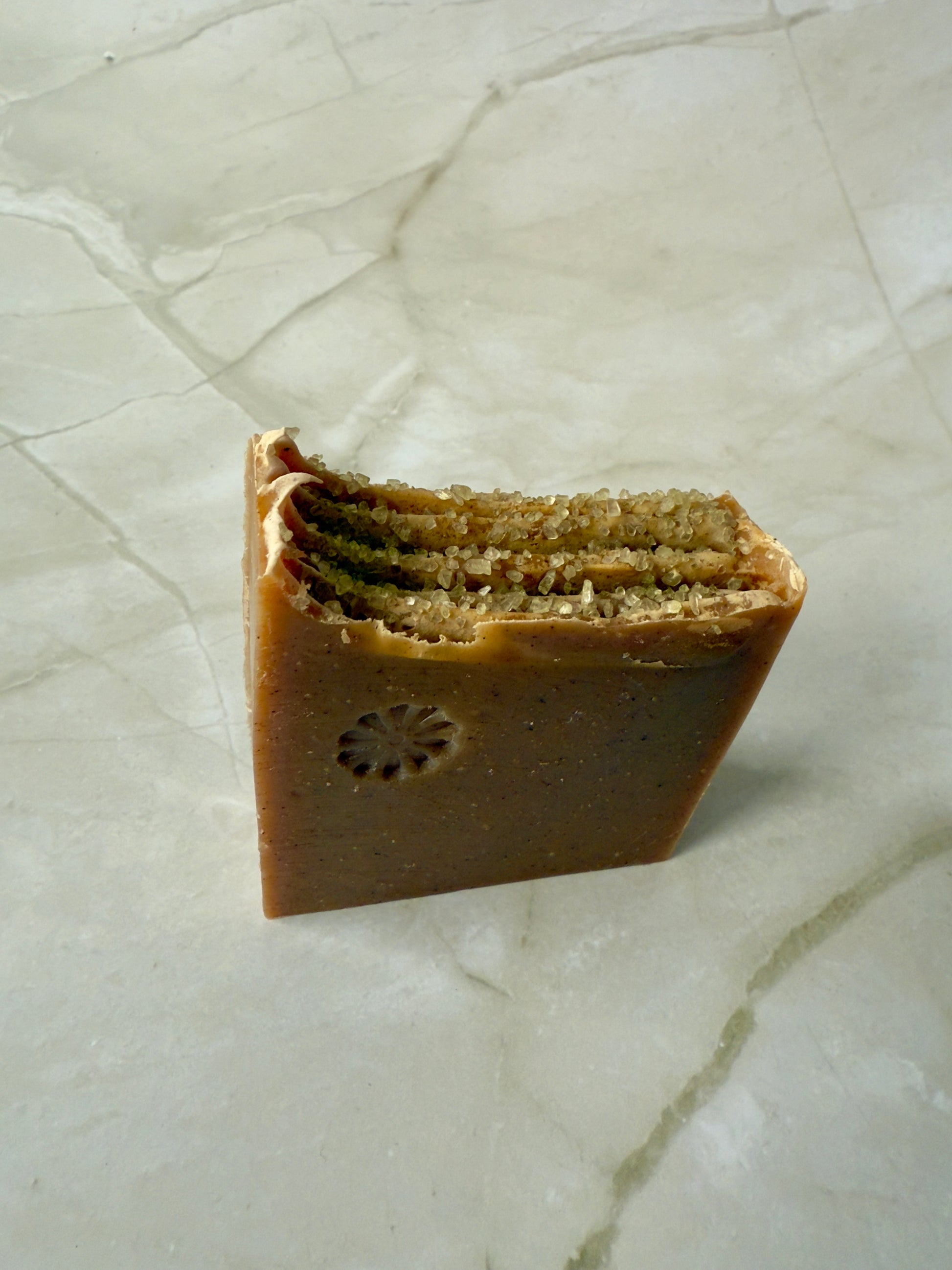 Brown artisan fig and amber soap bars with coarse salt on a marble background.