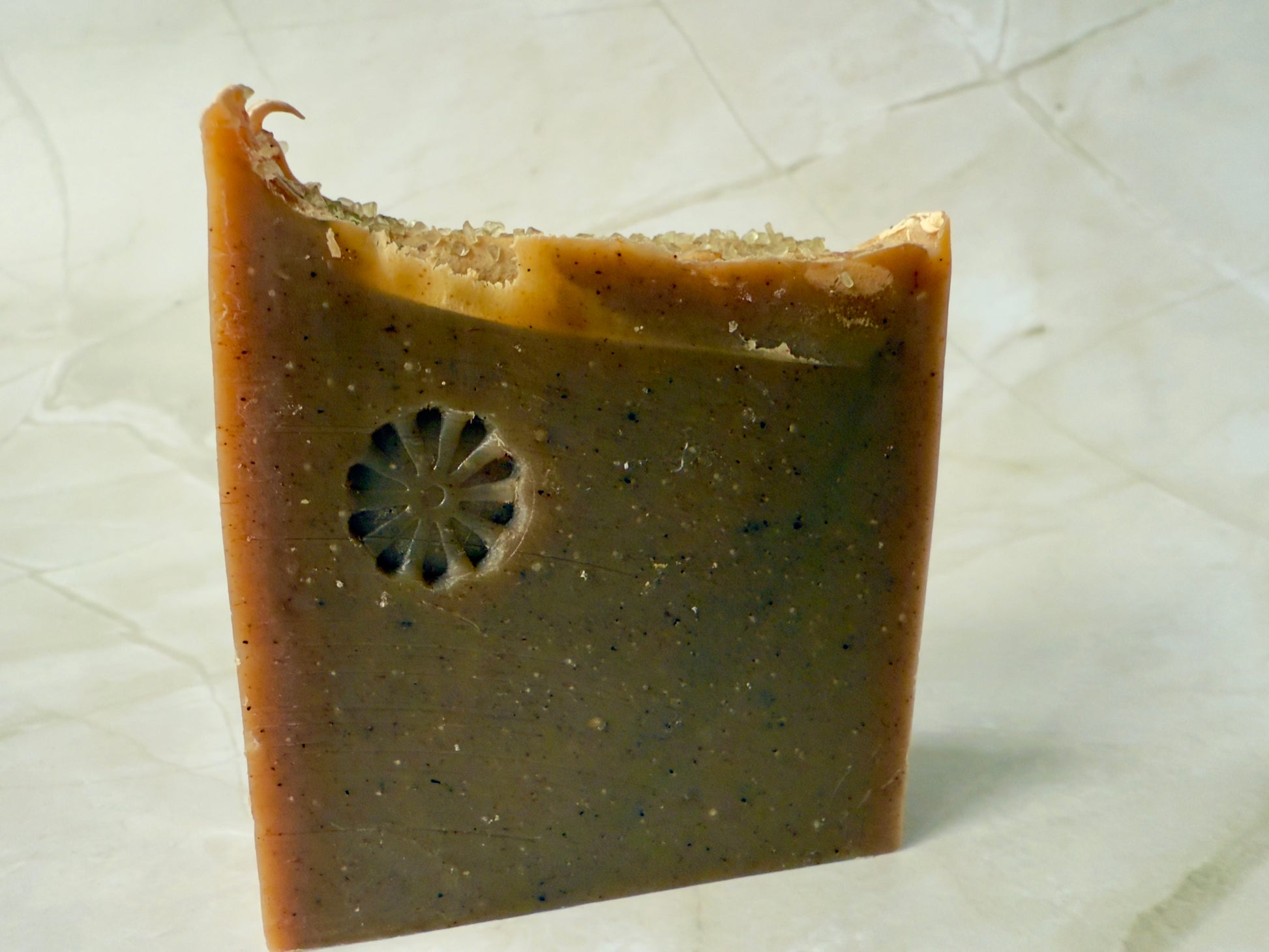 Brown artisan fig and amber soap bars with coarse salt on a marble background.