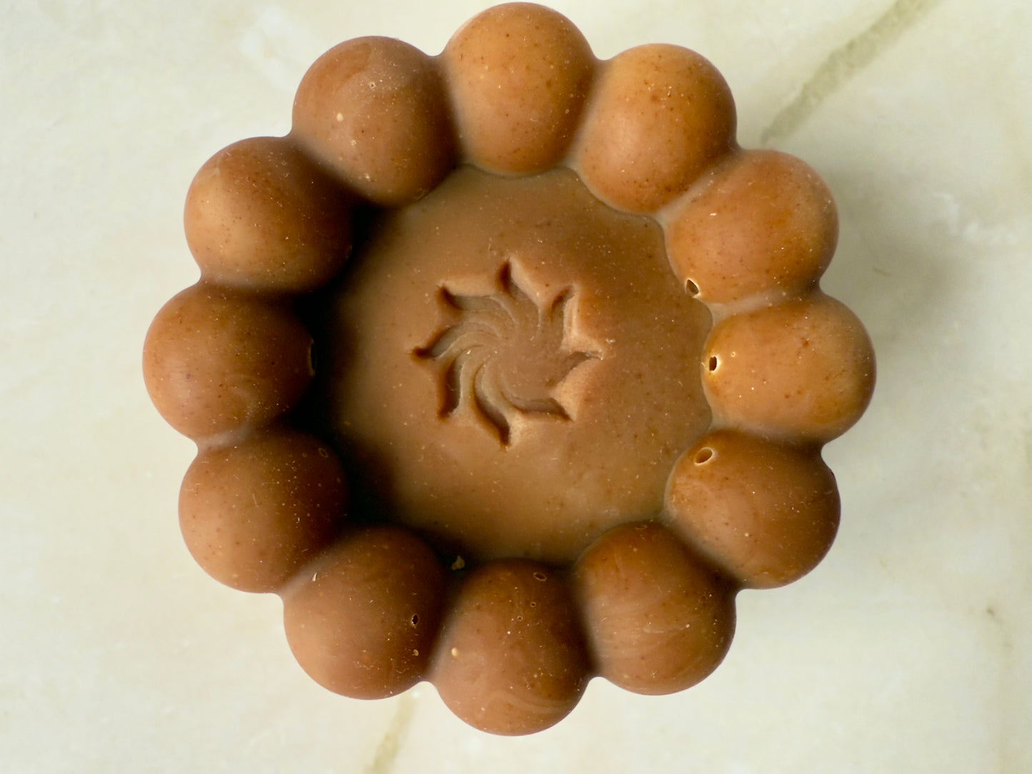 Brown artisan soap bars and round pudding-style bar with natural speckling on a marble background.
