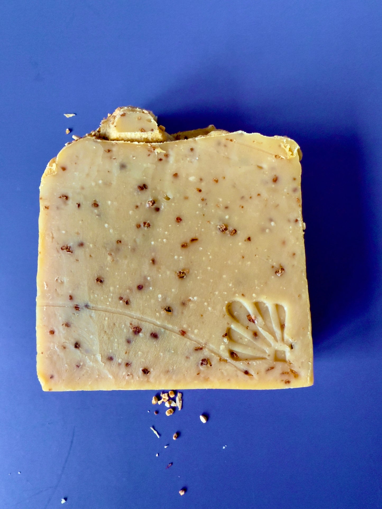 Golden citrus soap bars with orange peel speckles and a textured peel topping on a deep blue background.