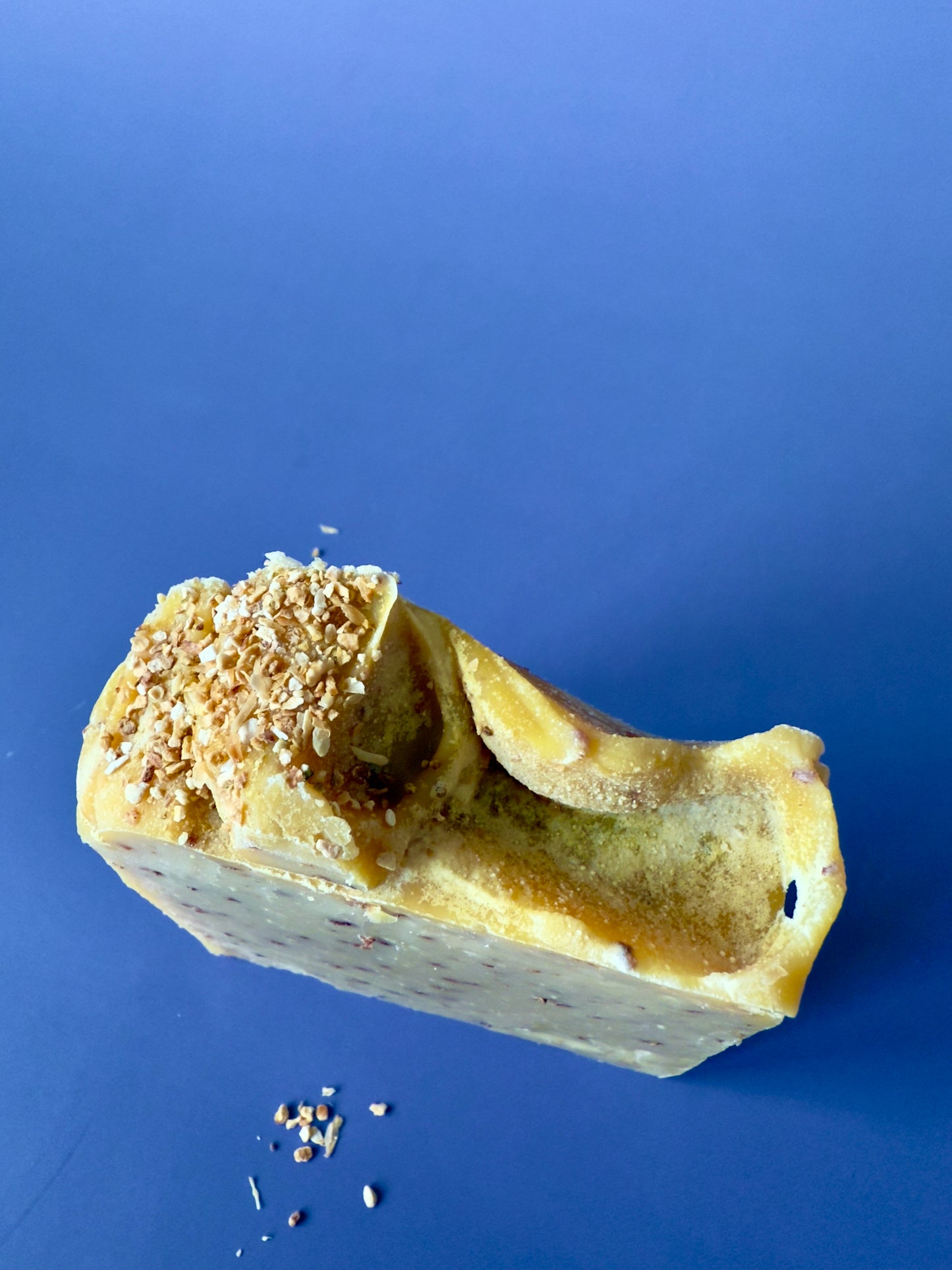 Golden citrus soap bars with orange peel speckles and a textured peel topping on a deep blue background.