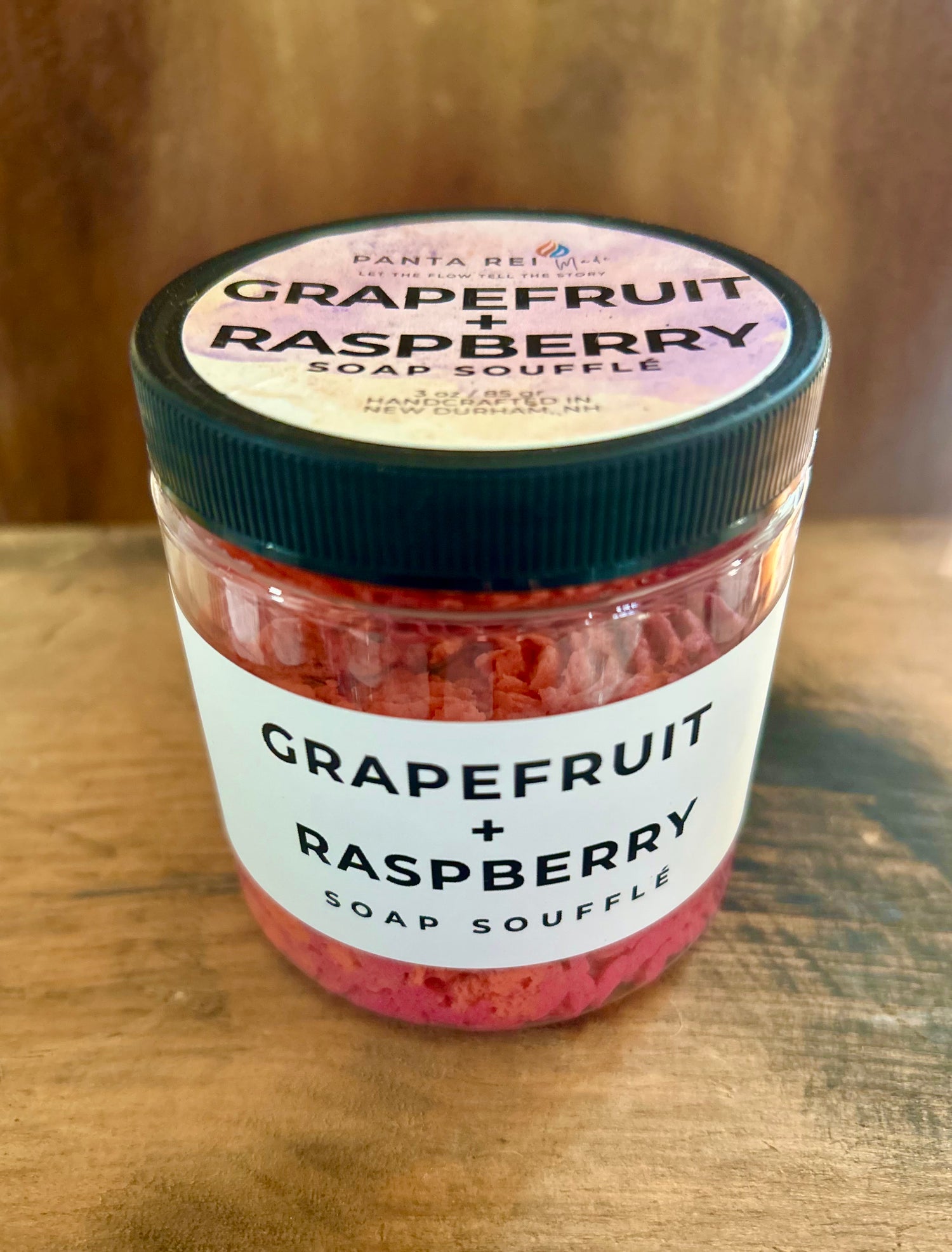 “Grapefruit + Raspberry Soap Soufflé in a clear jar with red and orange whipped swirl.”