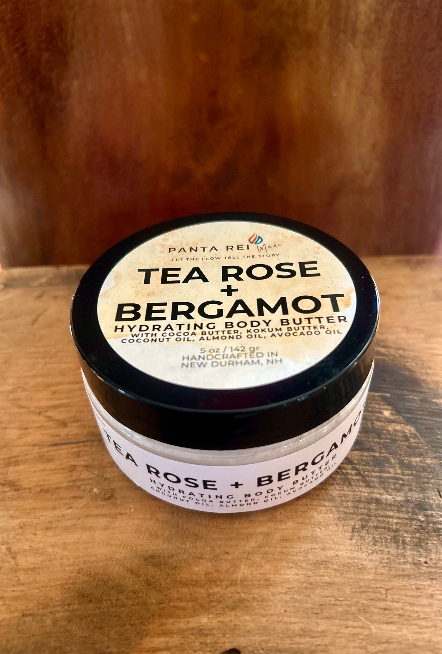Jar of tea rose and bergamot body butter on a wooden surface
Tea Rose + Bergamot hydrating body butter in a black-lid jar with a clean label, photographed on a wood background.