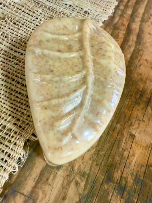 Leaf-shaped pet shampoo bar with visible oat texture on a wood and burlap background.