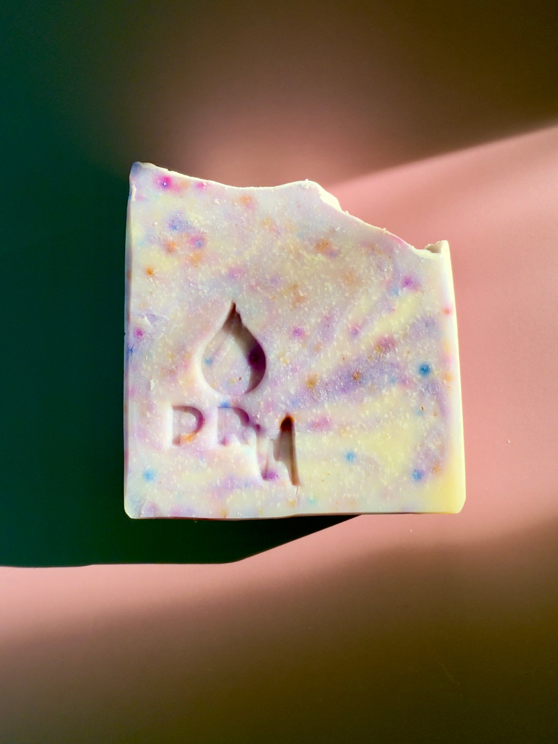 Rectangular handmade soap with a pale neutral tone, stamped with the PRM logo, photographed on a softly lit surface.