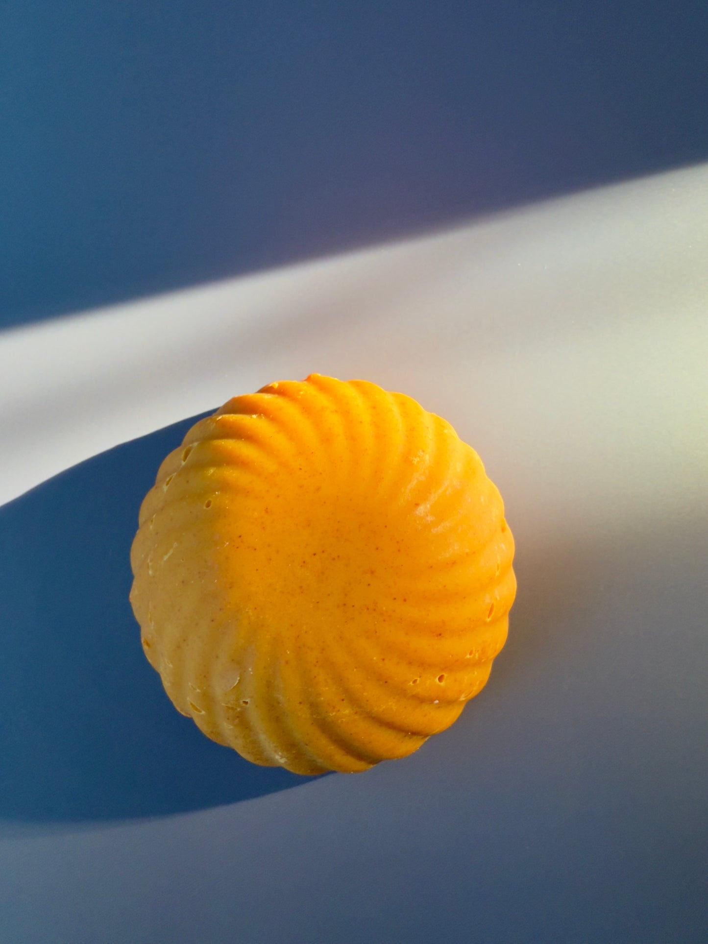 Round bar of soap with natural turmeric color on a blue background