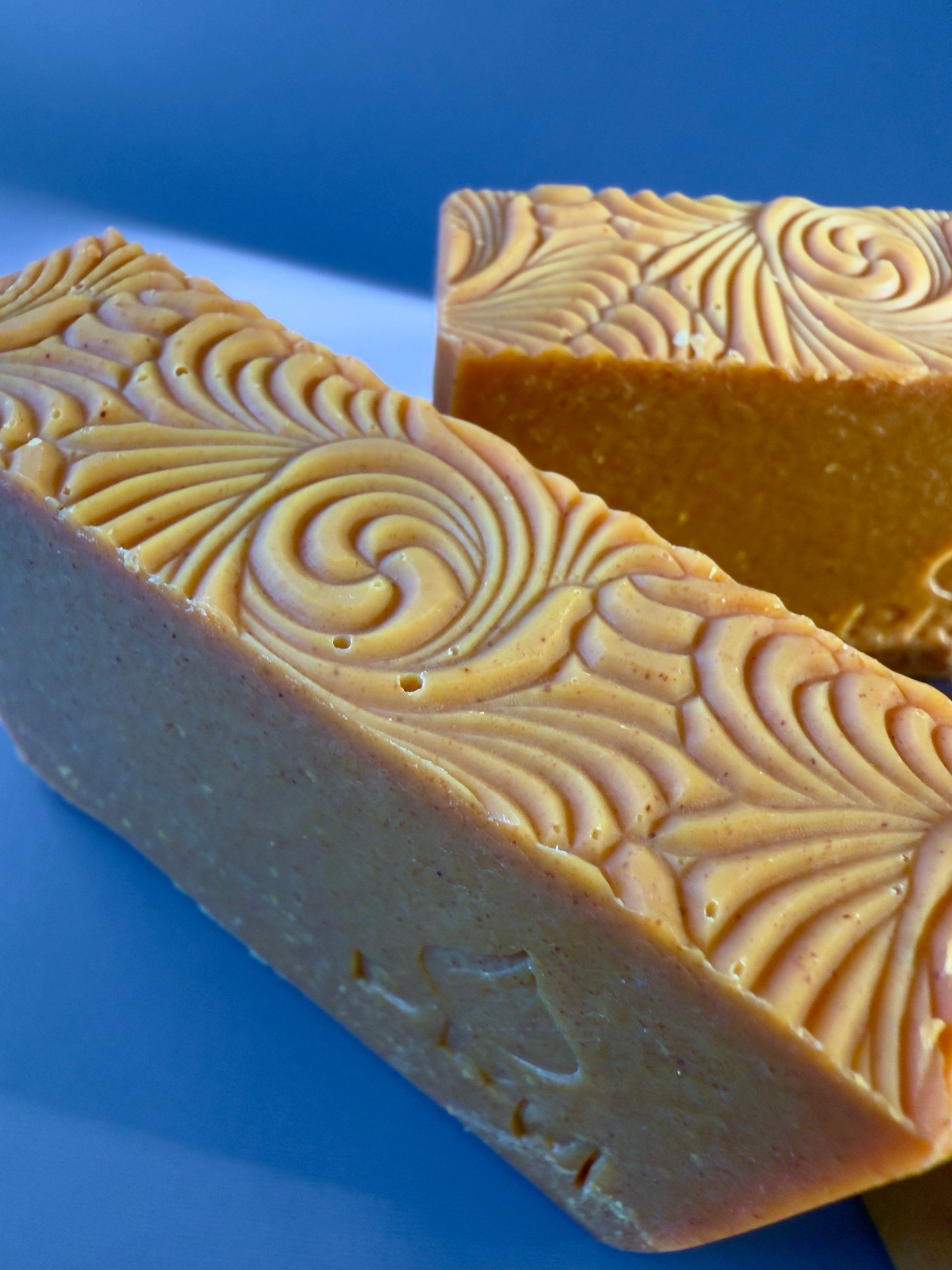 Two bars of soap with textured surface on a blue background
