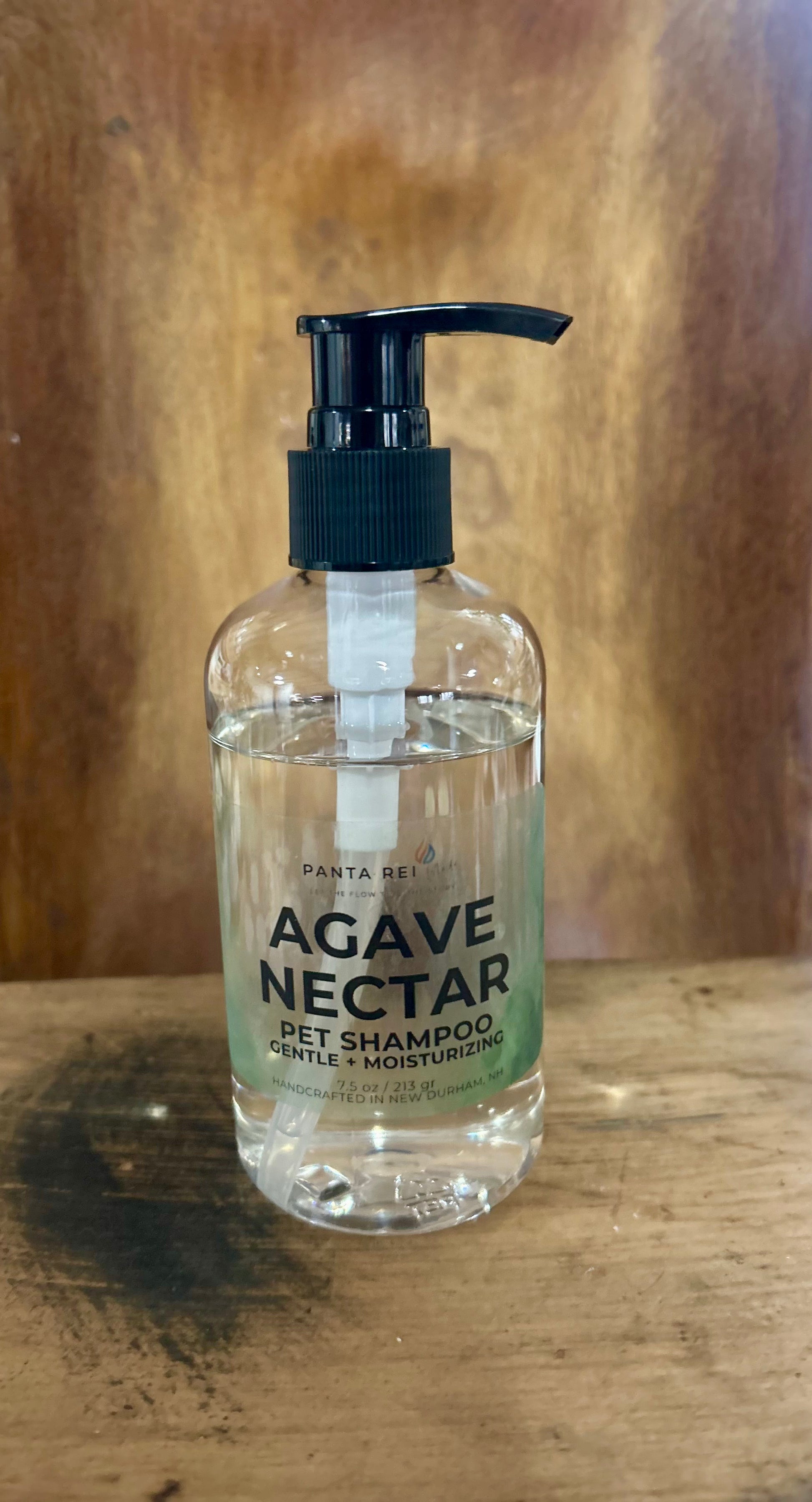 Clear pump bottle labeled Agave Nectar Pet Shampoo on a wooden surface.