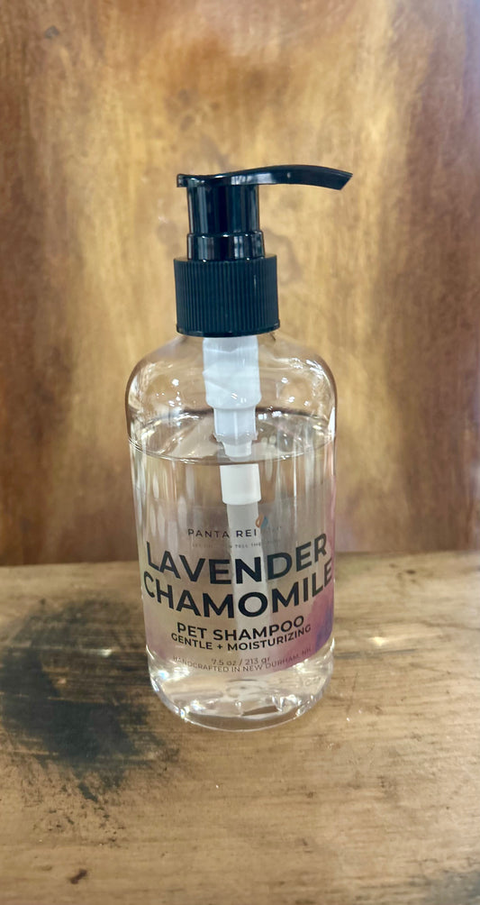 Clear pump bottle labeled Lavender + Chamomile Pet Shampoo on a wooden surface.