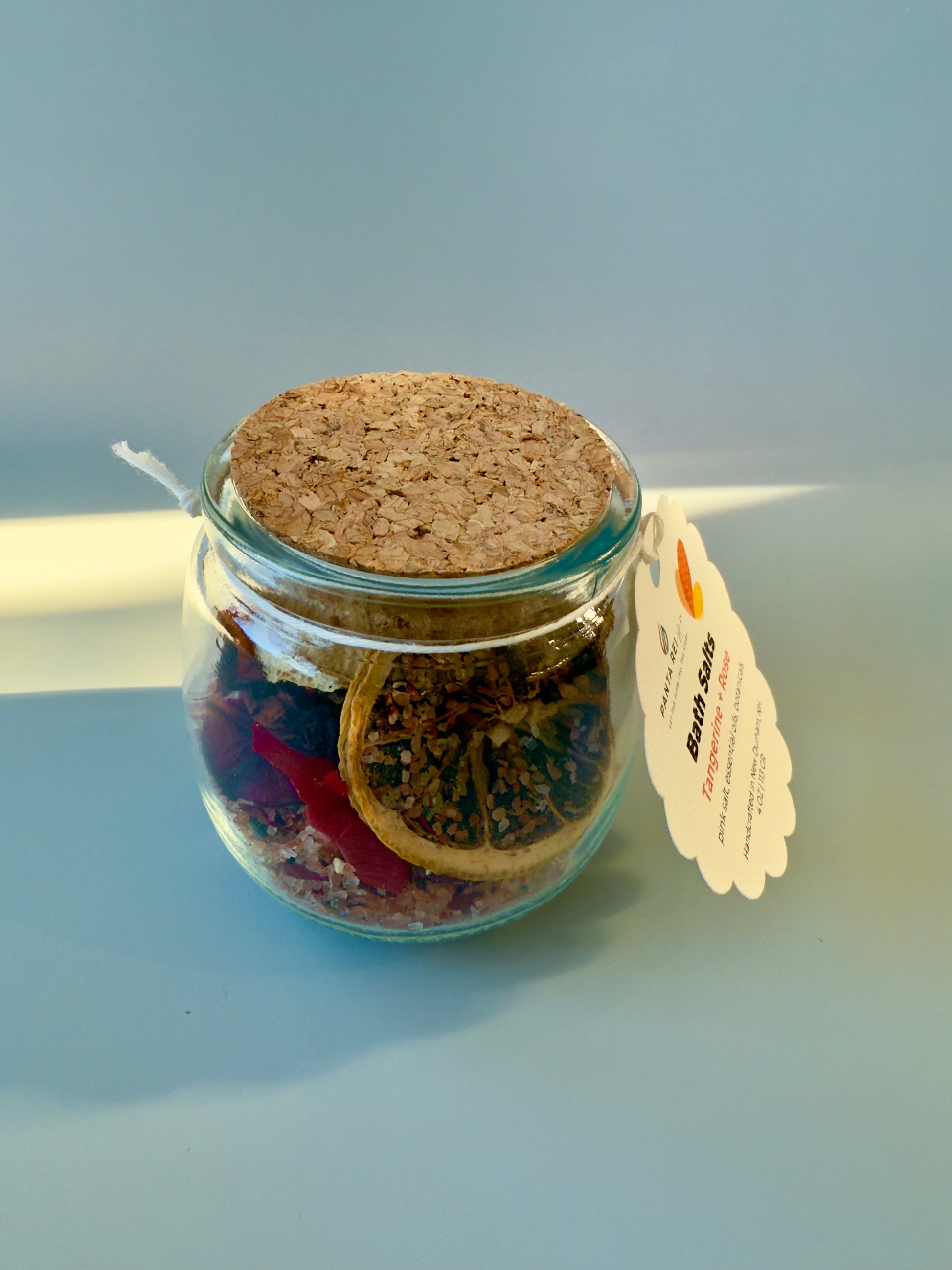 Side view of Tangerine + Rose bath salts jar showing botanical layers and cork top.