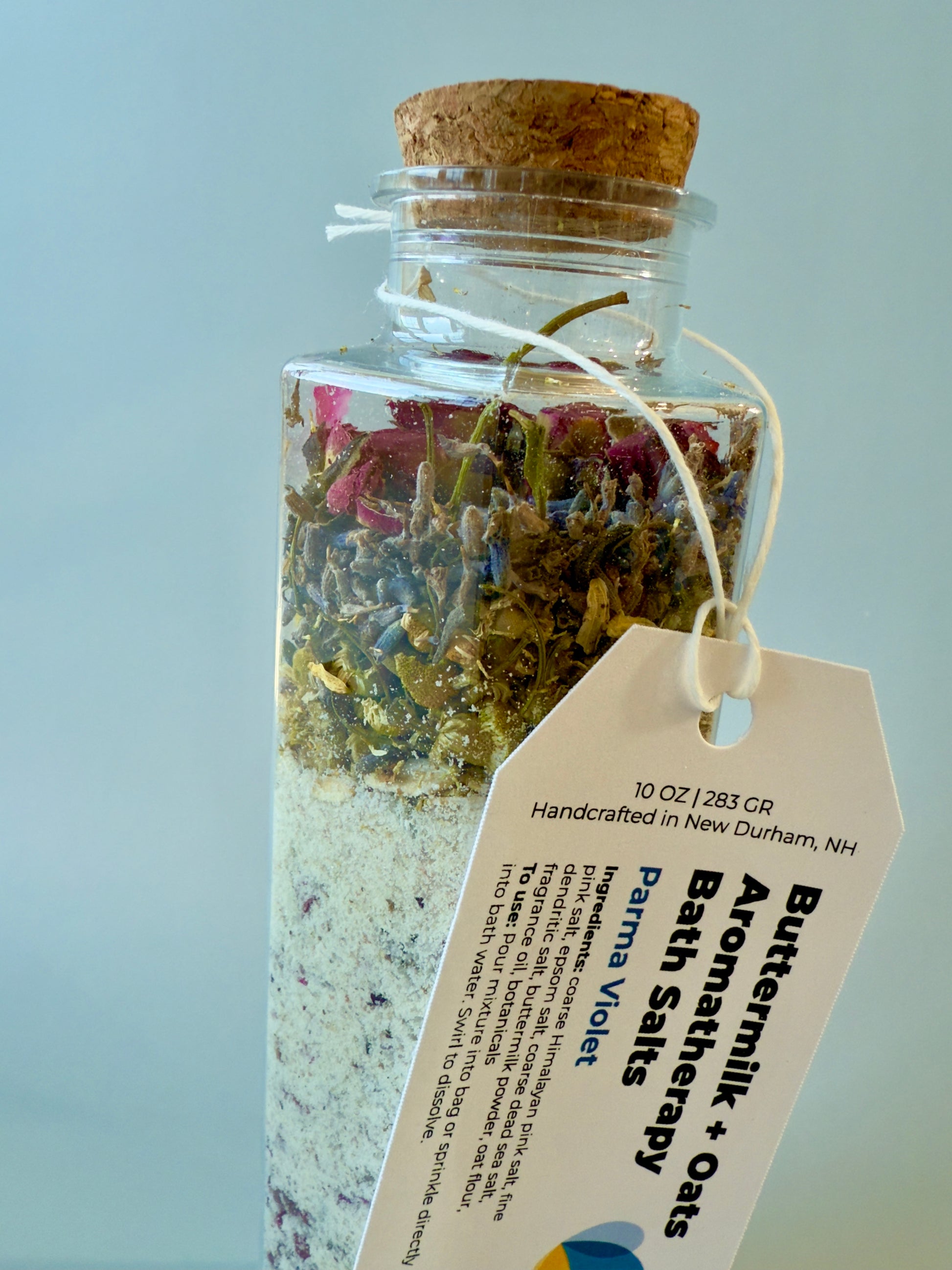 Close-up of bath salts bottle showing botanical layer and Parma Violet product tag.