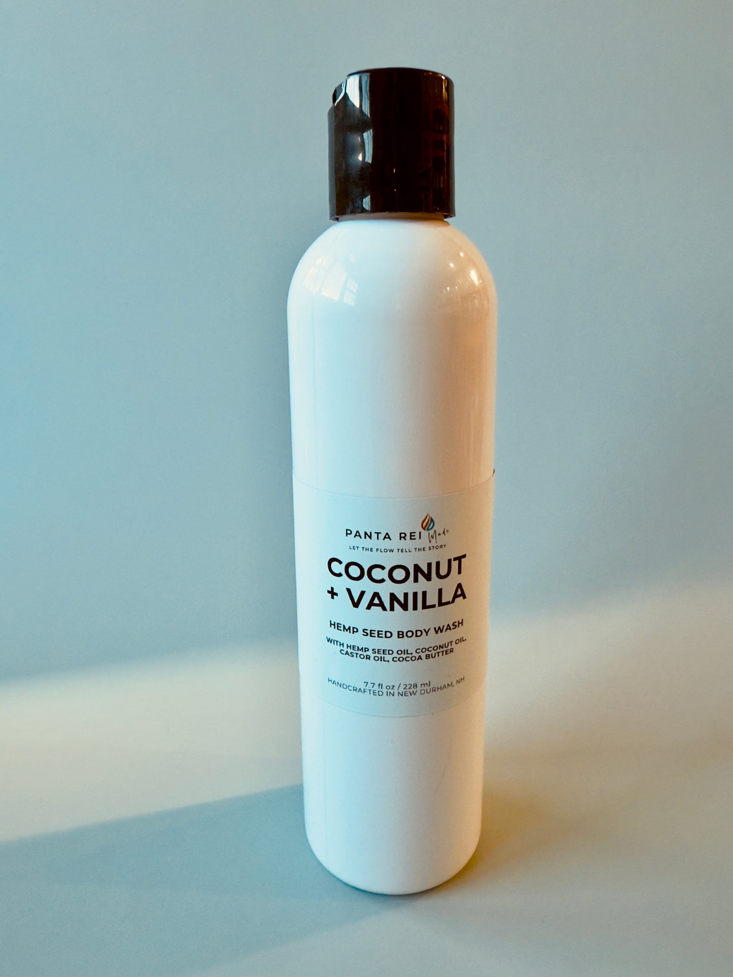 White bottle with black cap labeled Coconut + Vanilla Hemp Seed Body Wash.