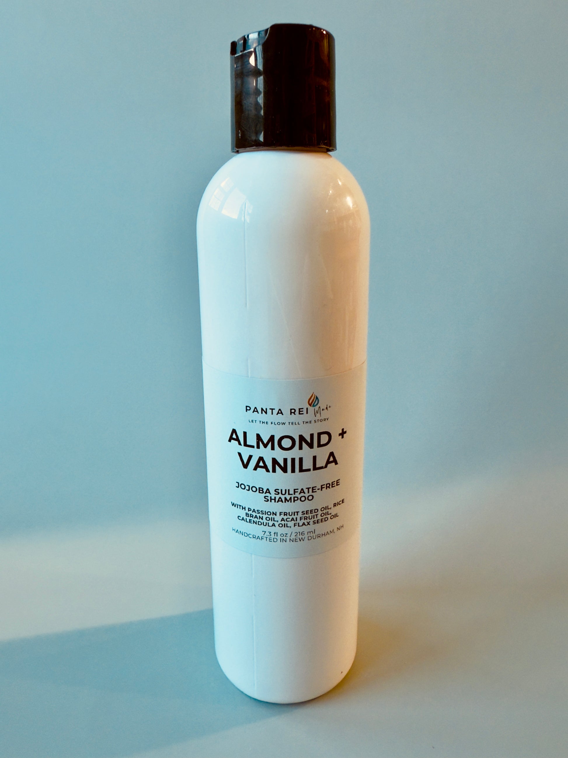 White bottle with black cap labeled Almond + Vanilla sulfate-free shampoo.