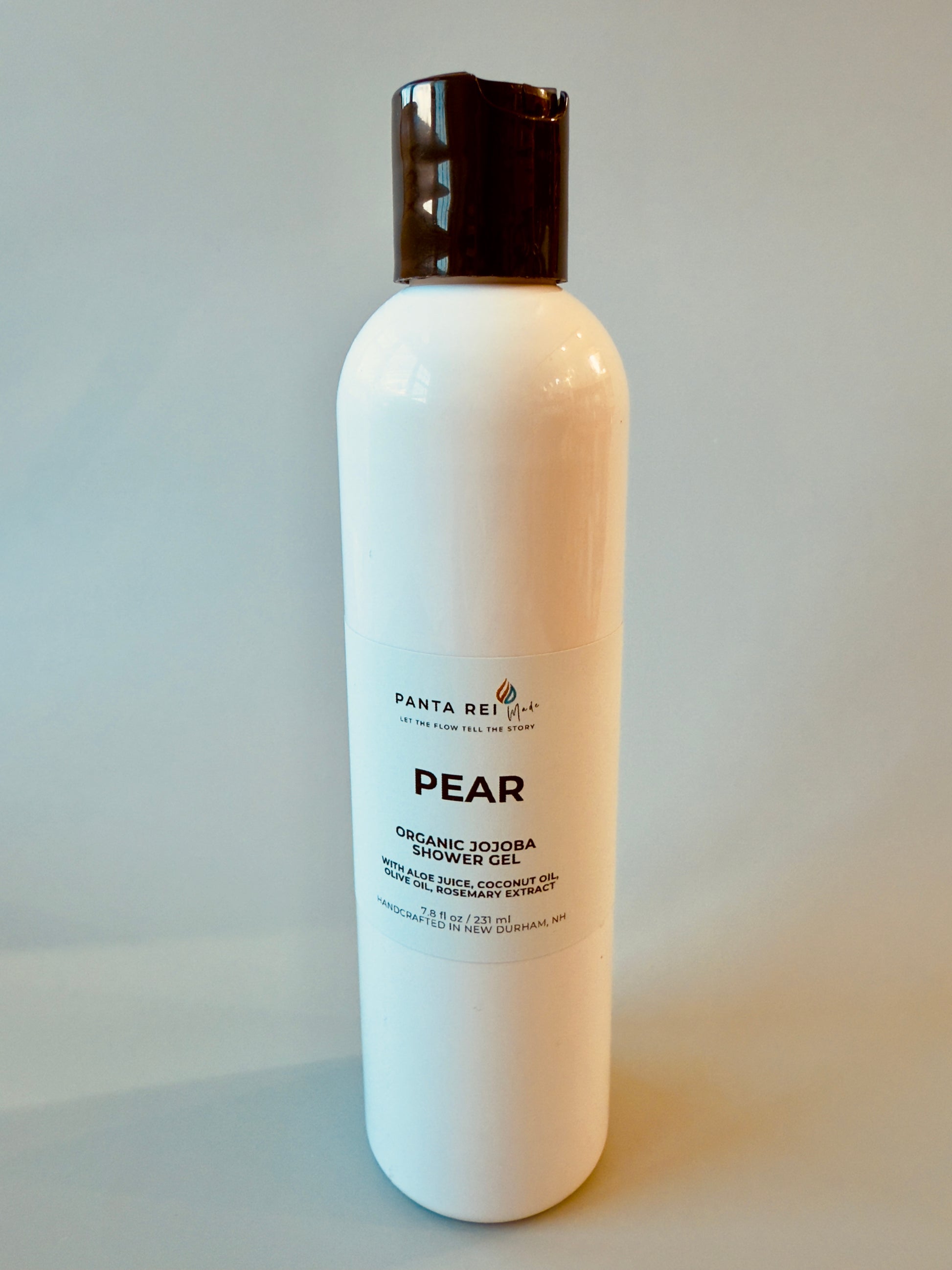 White bottle with black cap labeled Pear Organic Jojoba Shower Gel.