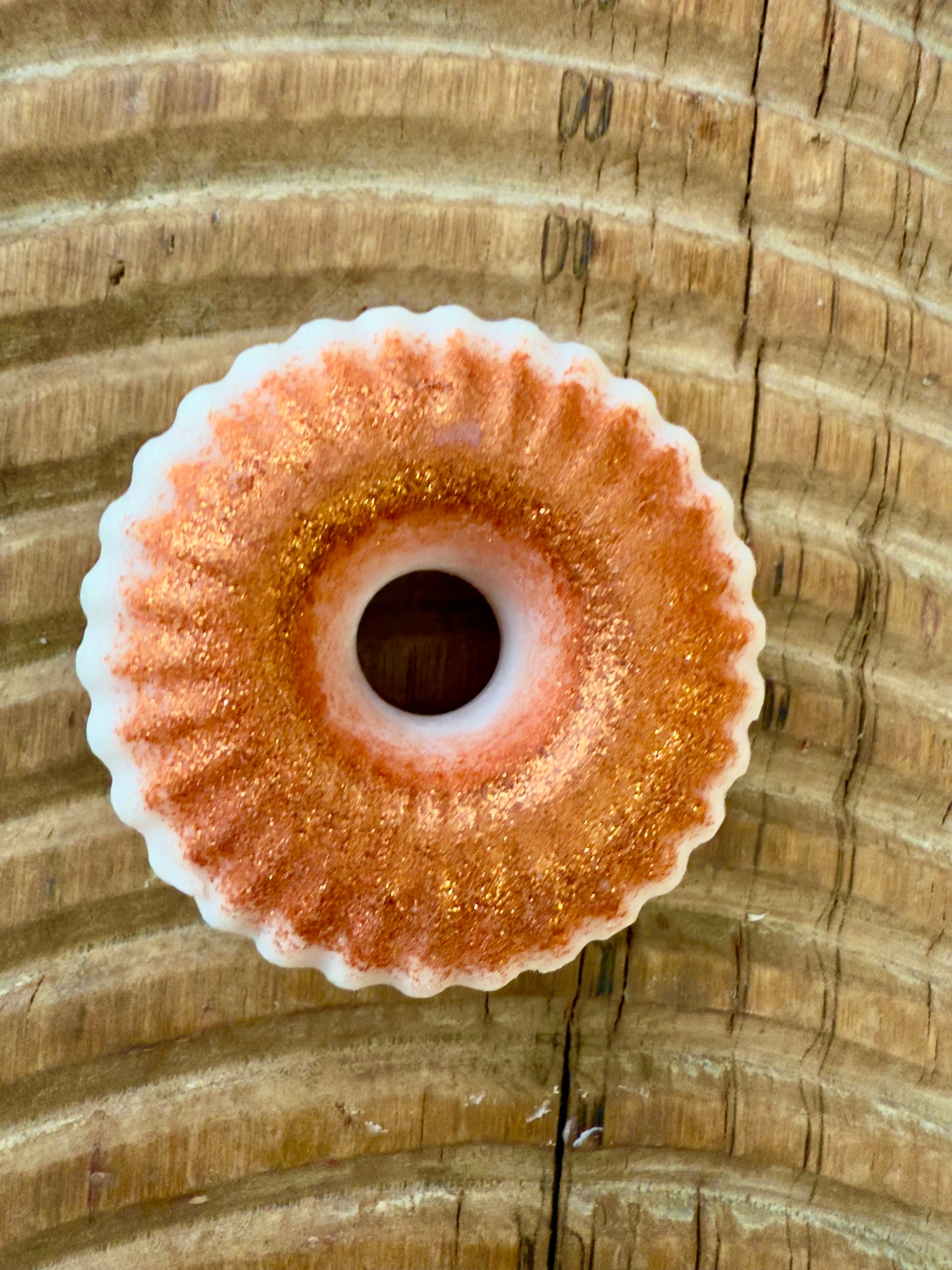 Ridged shampoo bar in shimmering copper with a white underside, shaped like a doughnut with fluted edges.