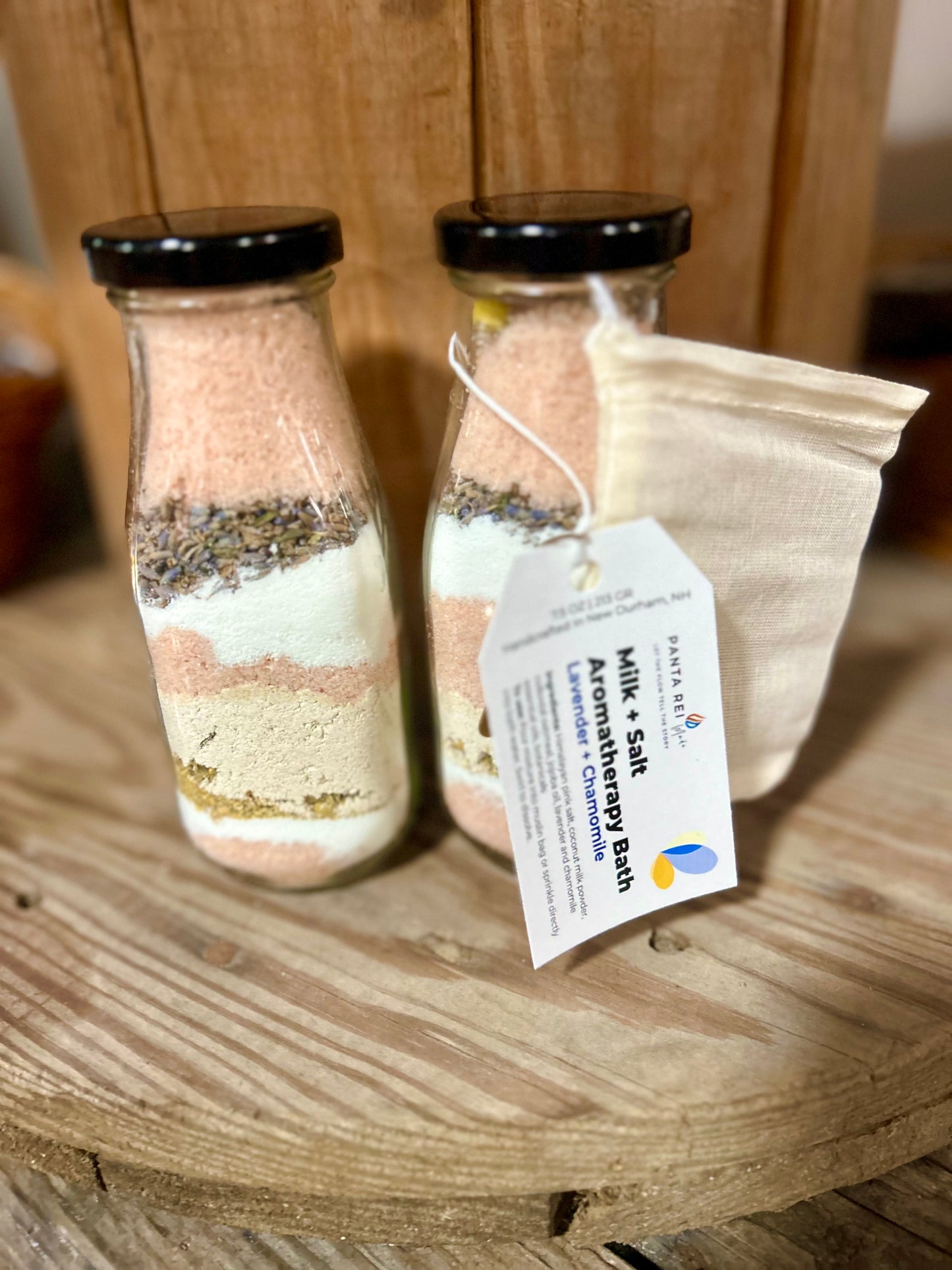 Glass milk bottles of lavender and chamomile aromatherapy bath mix with product tag attached.