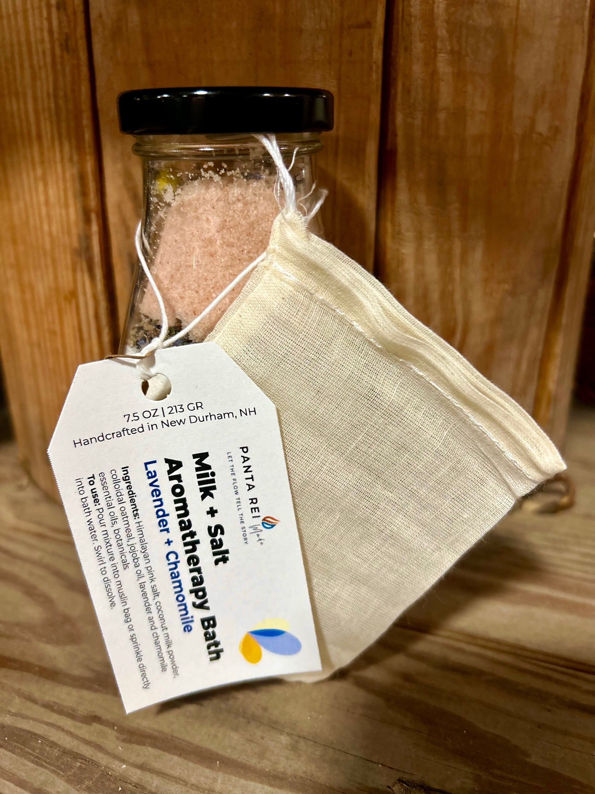 Glass milk bottle of lavender and chamomile aromatherapy bath mix with product tag and muslin bag attached.