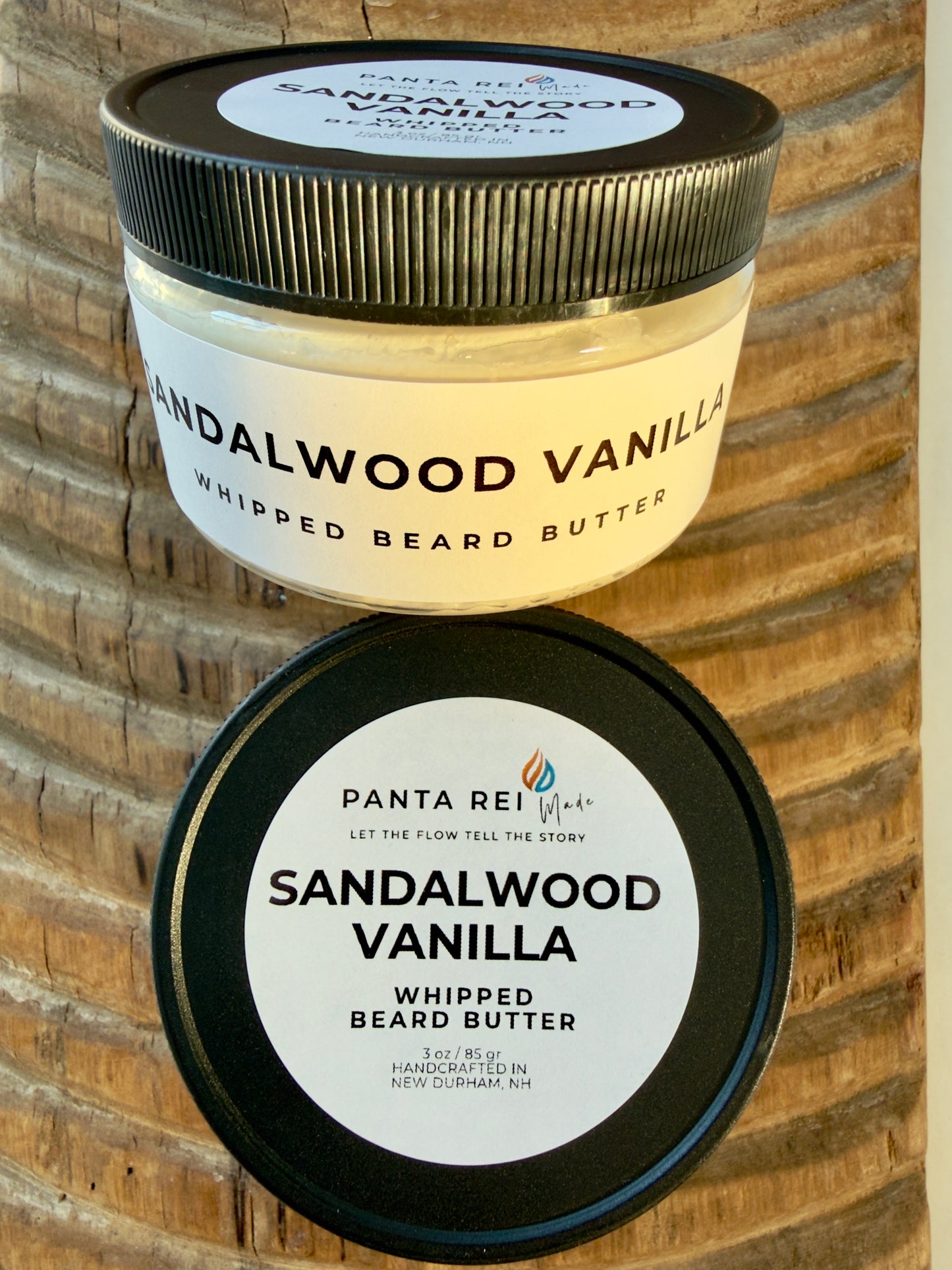 Sandalwood Vanilla whipped beard butter in matte black-lidded jar on carved wood background.