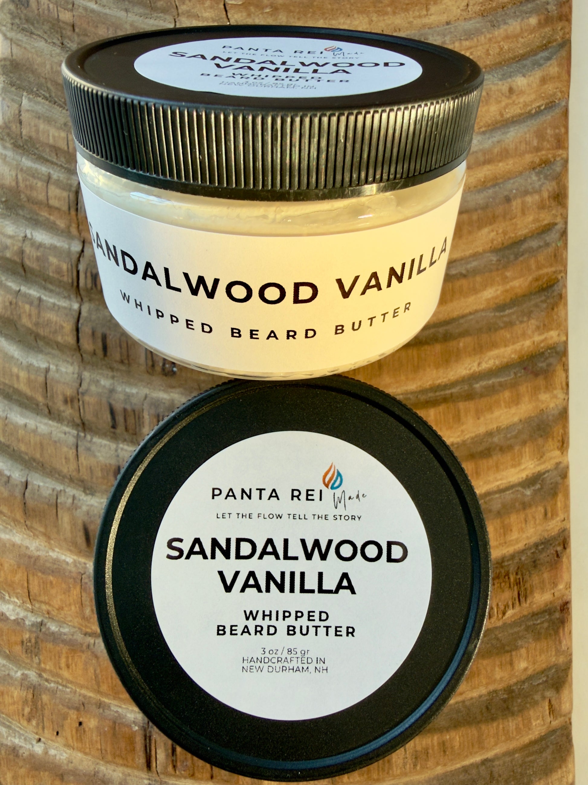 Sandalwood Vanilla whipped beard butter in matte black-lidded jar on carved wood background.
