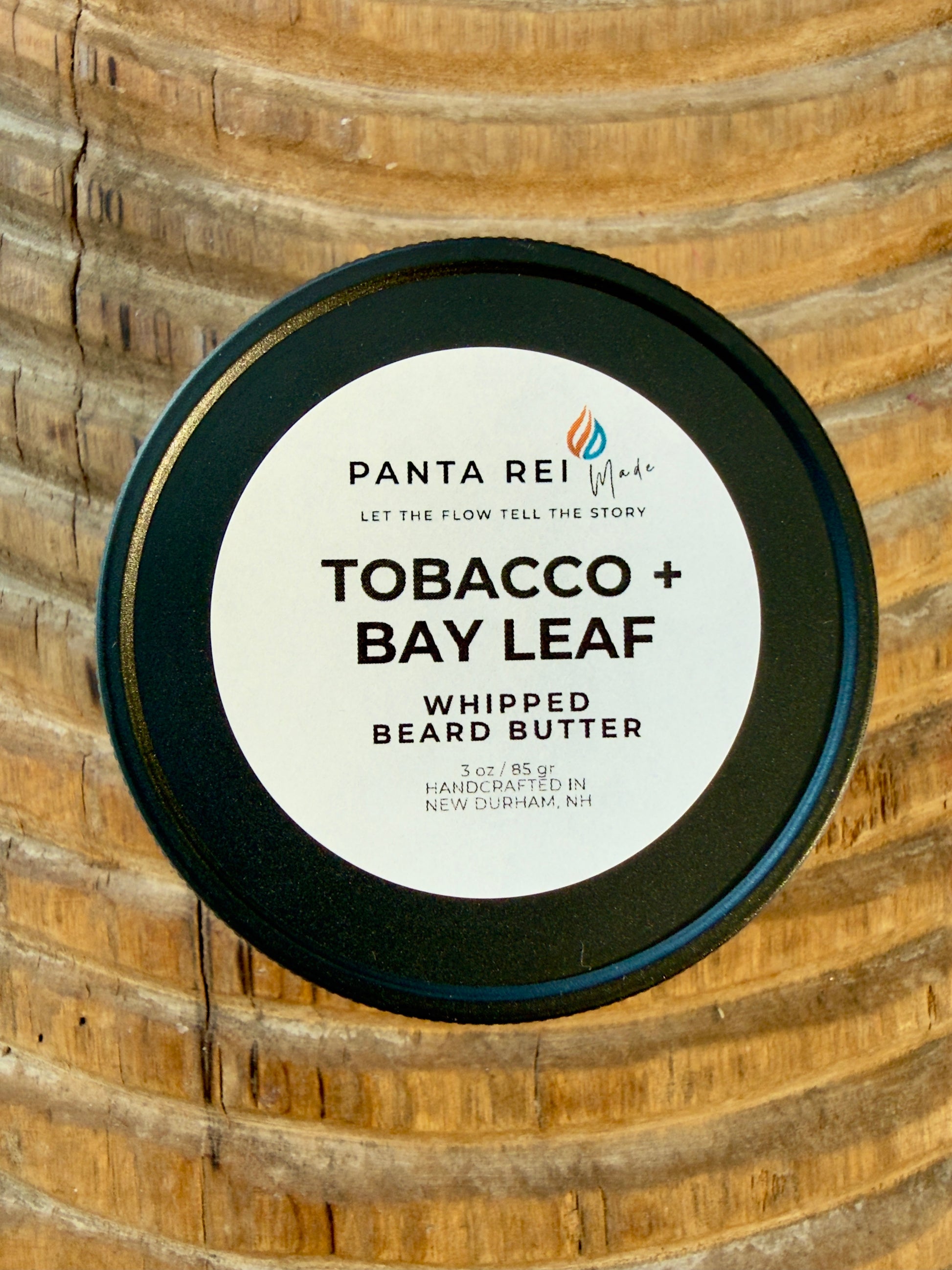 Tobacco + Bay Leaf whipped beard butter jar on carved wood background.