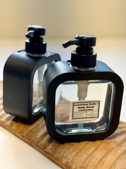 Two Awakening Bath + Body Wash bottles displayed on a wooden board