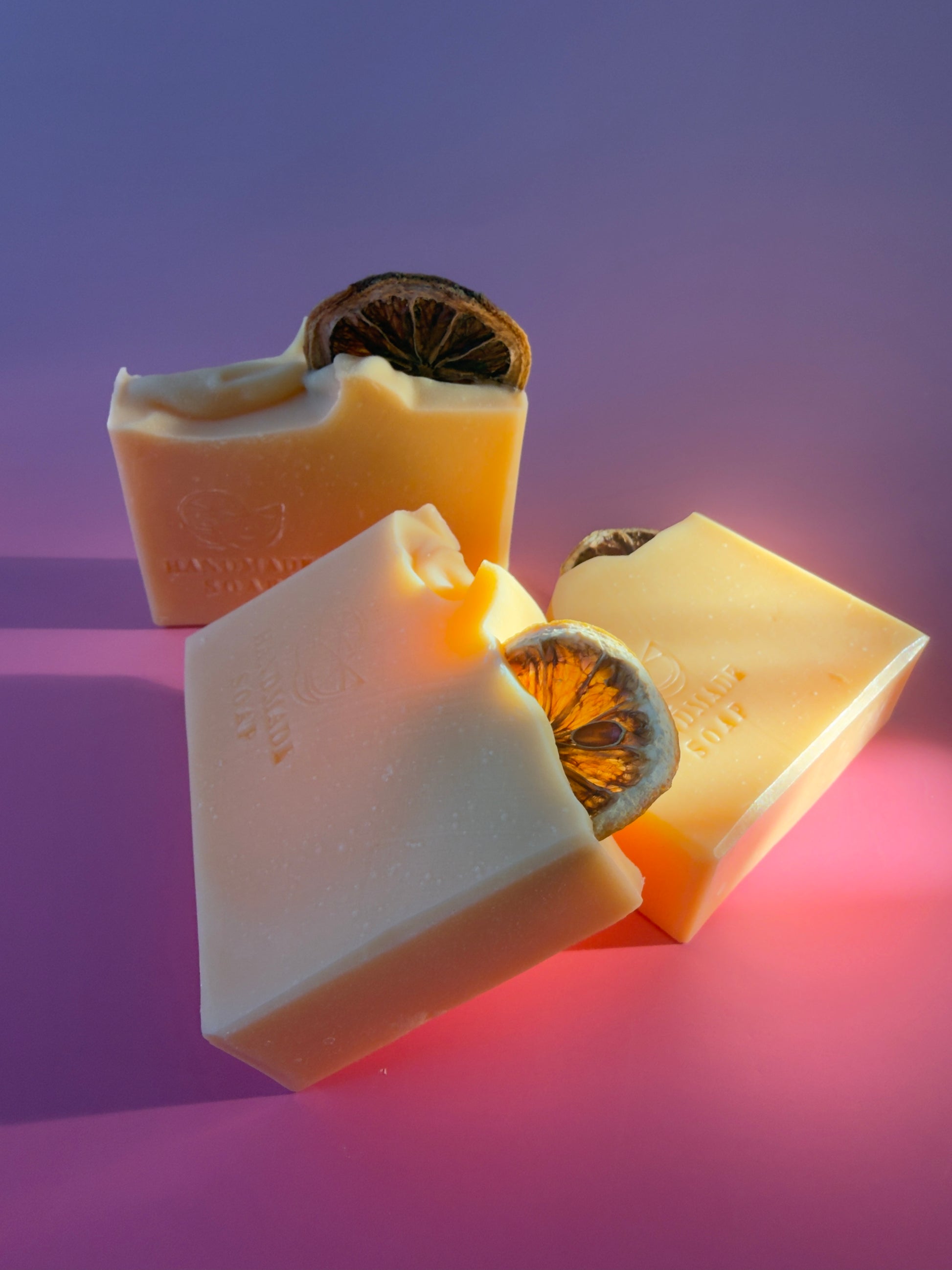 Pink grapefruit beef tallow soap bars arranged on a pink and purple background