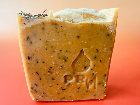 Hand-cut Lavender Mint soap bars with a warm golden tone, visible spearmint leaf flecks throughout, and dried spearmint leaves on top against a soft gradient background.